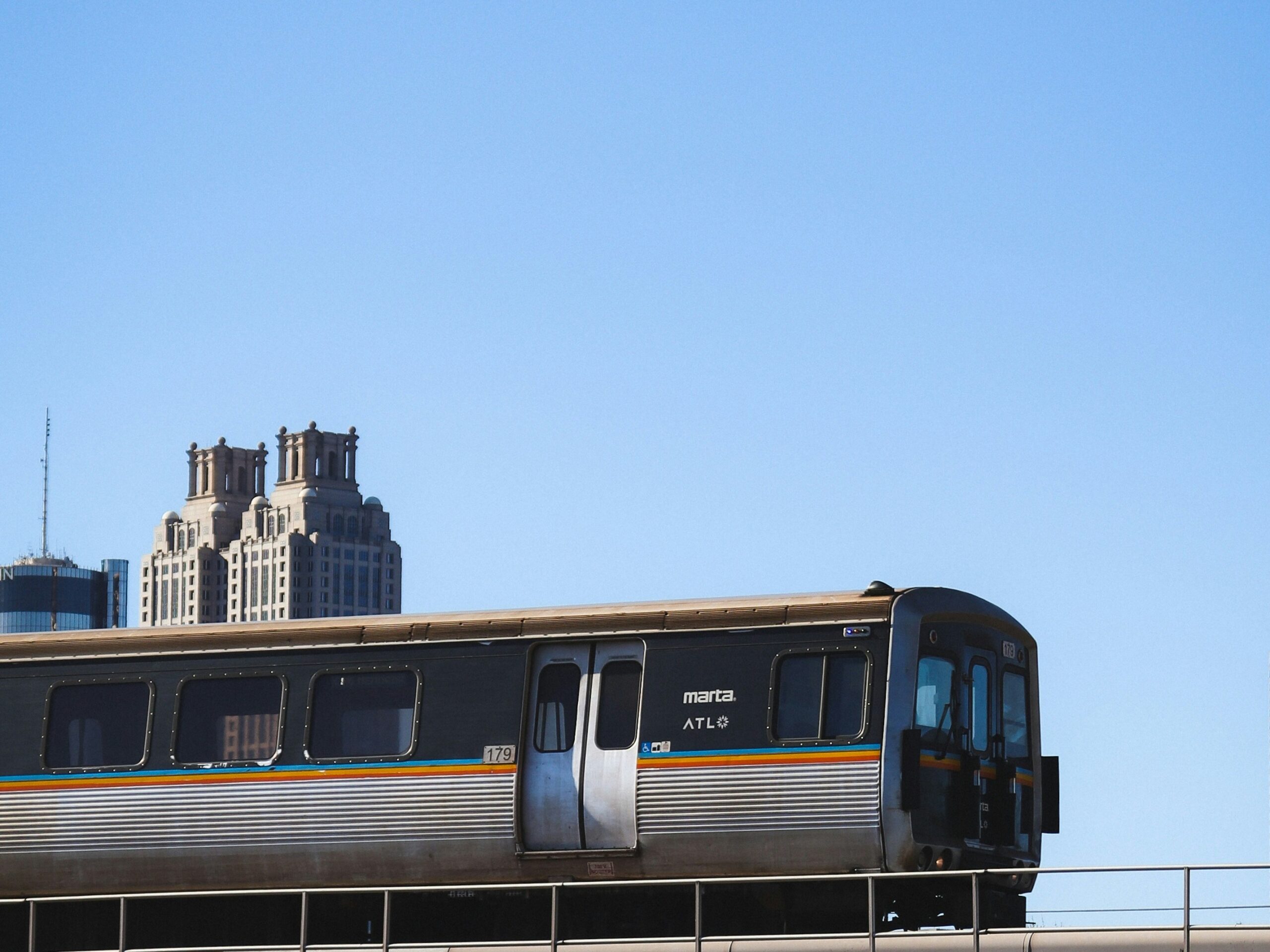 The image shows a MARTA heavy-rail train passing the Downtown Atlanta skyline.