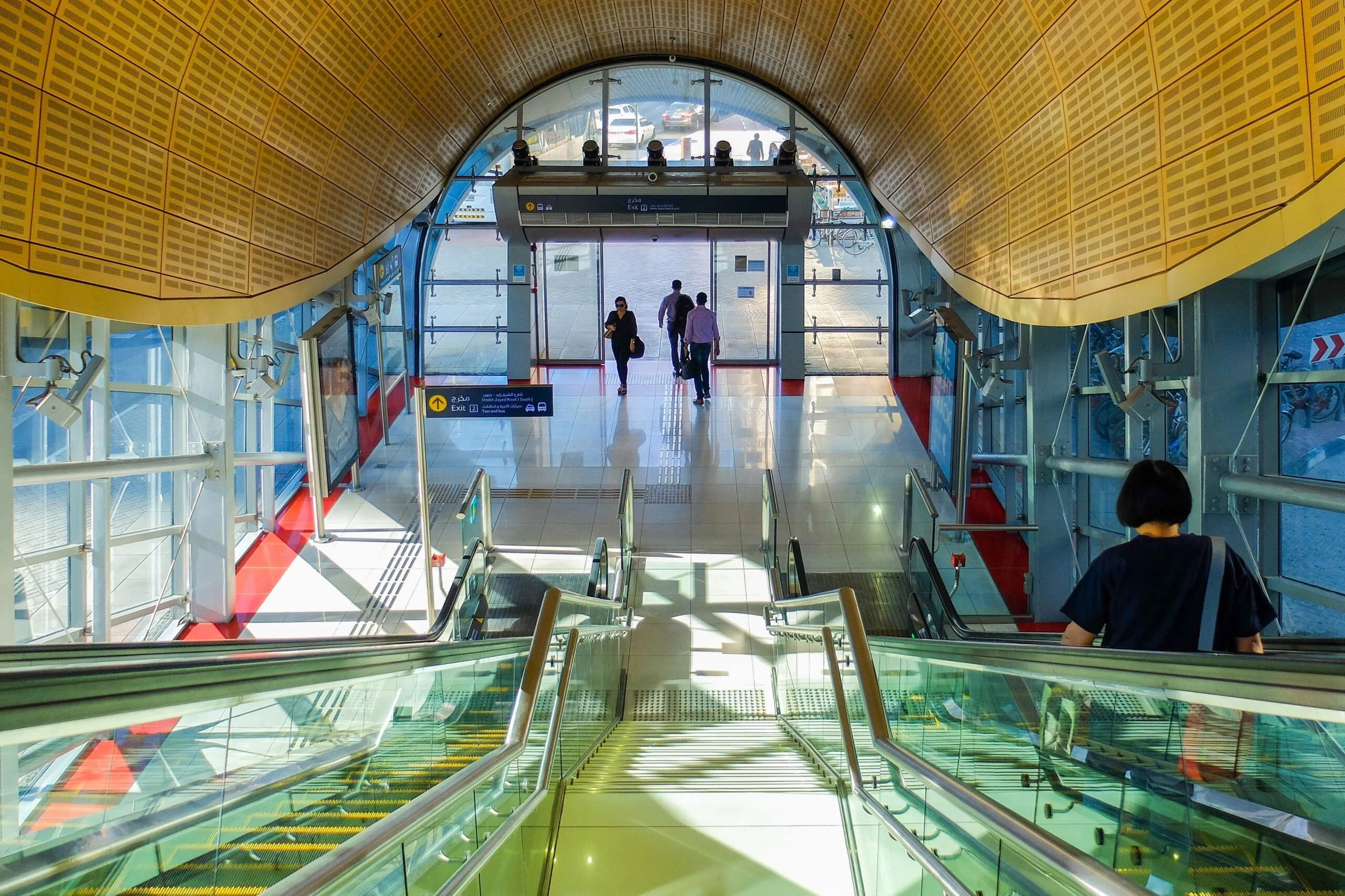 The picture shows the interior of a Dubai Metro station with its striking golden shell-shaped roof and escalators, where travelers buy and top up their Nol Card for the Dubai Metro.