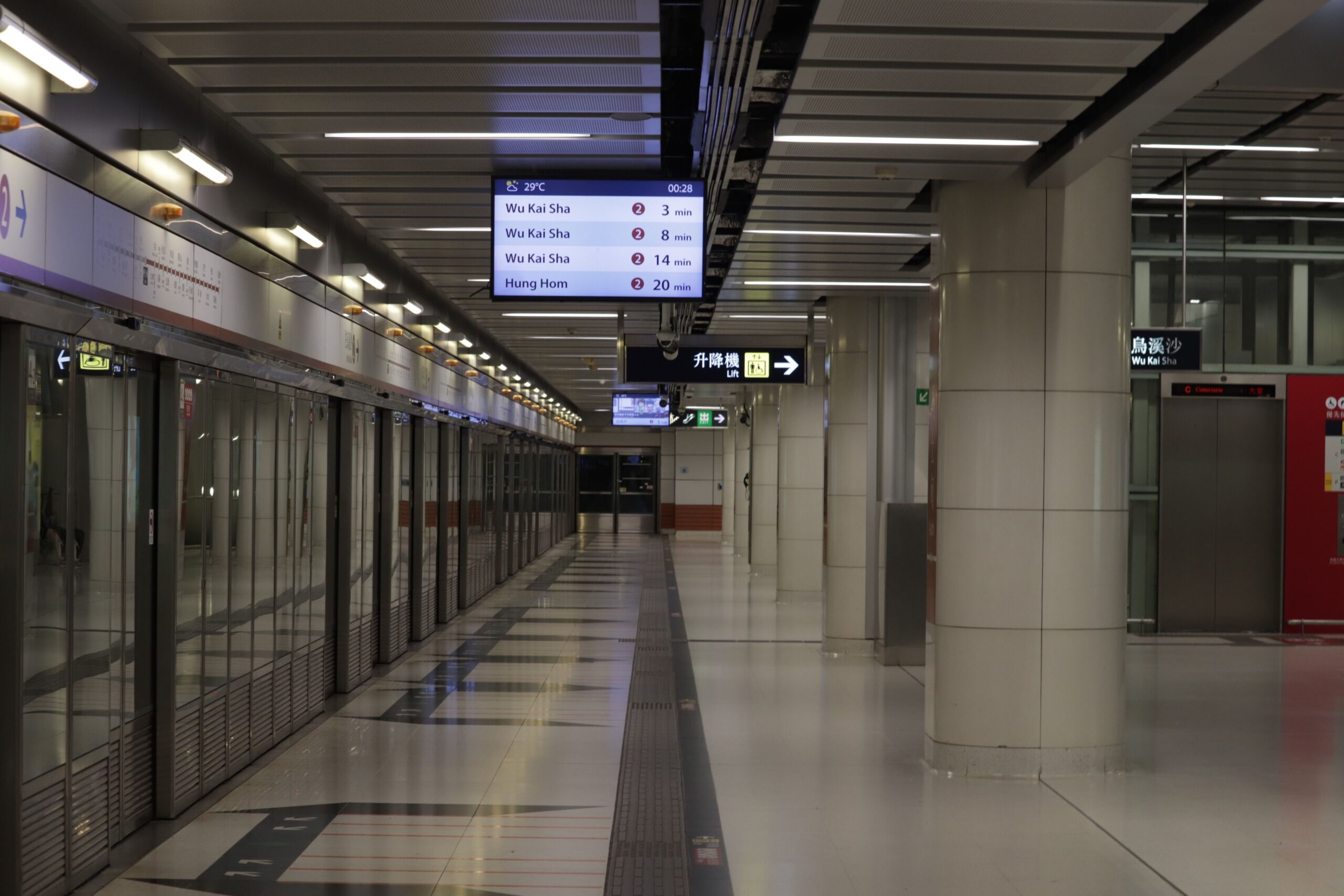 Auf dem Bild sehen Sie den leeren Bahnsteig und die zweisprachige Beschilderung der Station Wu Kai Sha als Motiv zum Hongkong-U-Bahn-Plan.