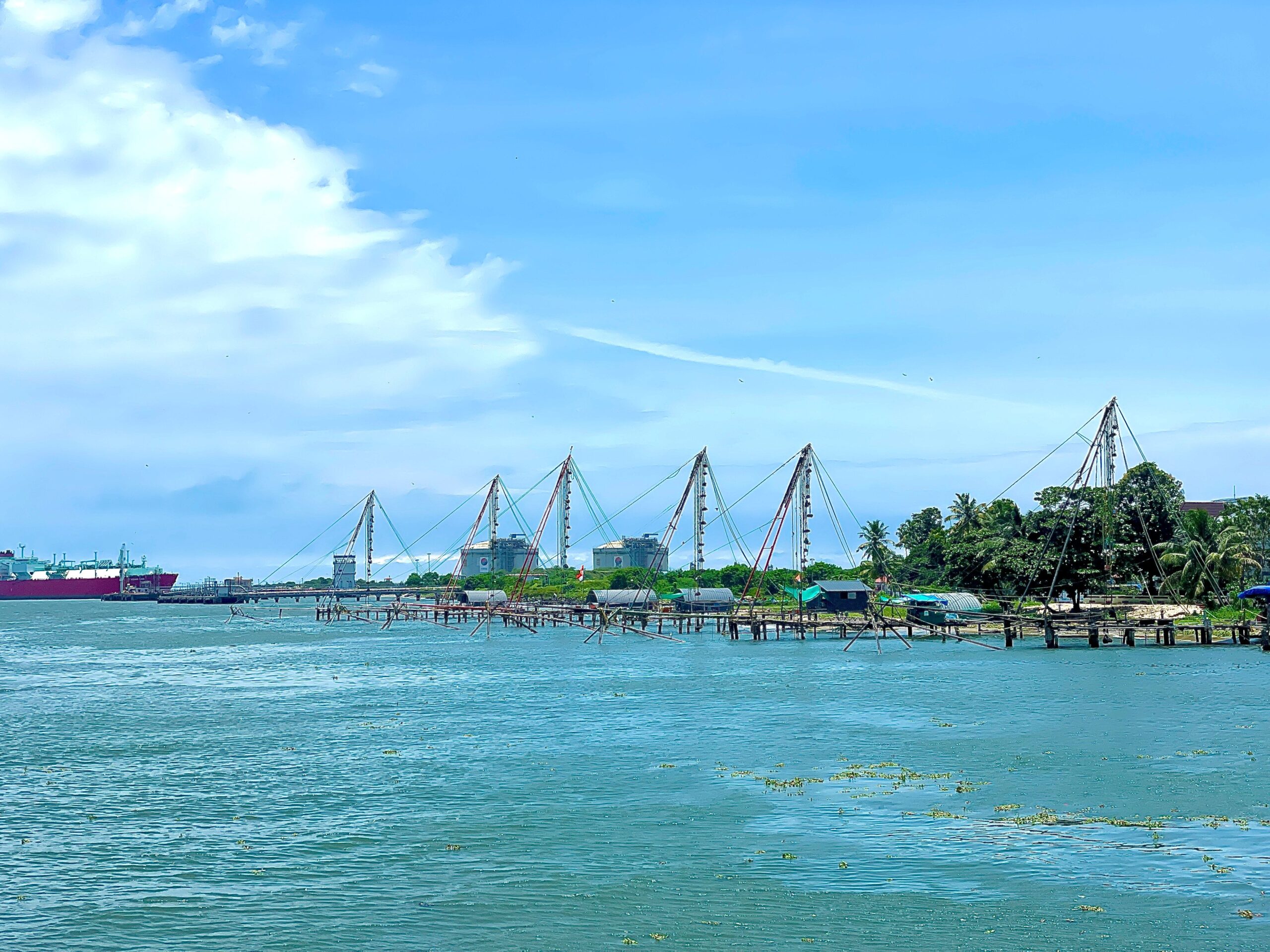 The image shows traditional Chinese fishing nets beside the waterfront at Fort Kochi.