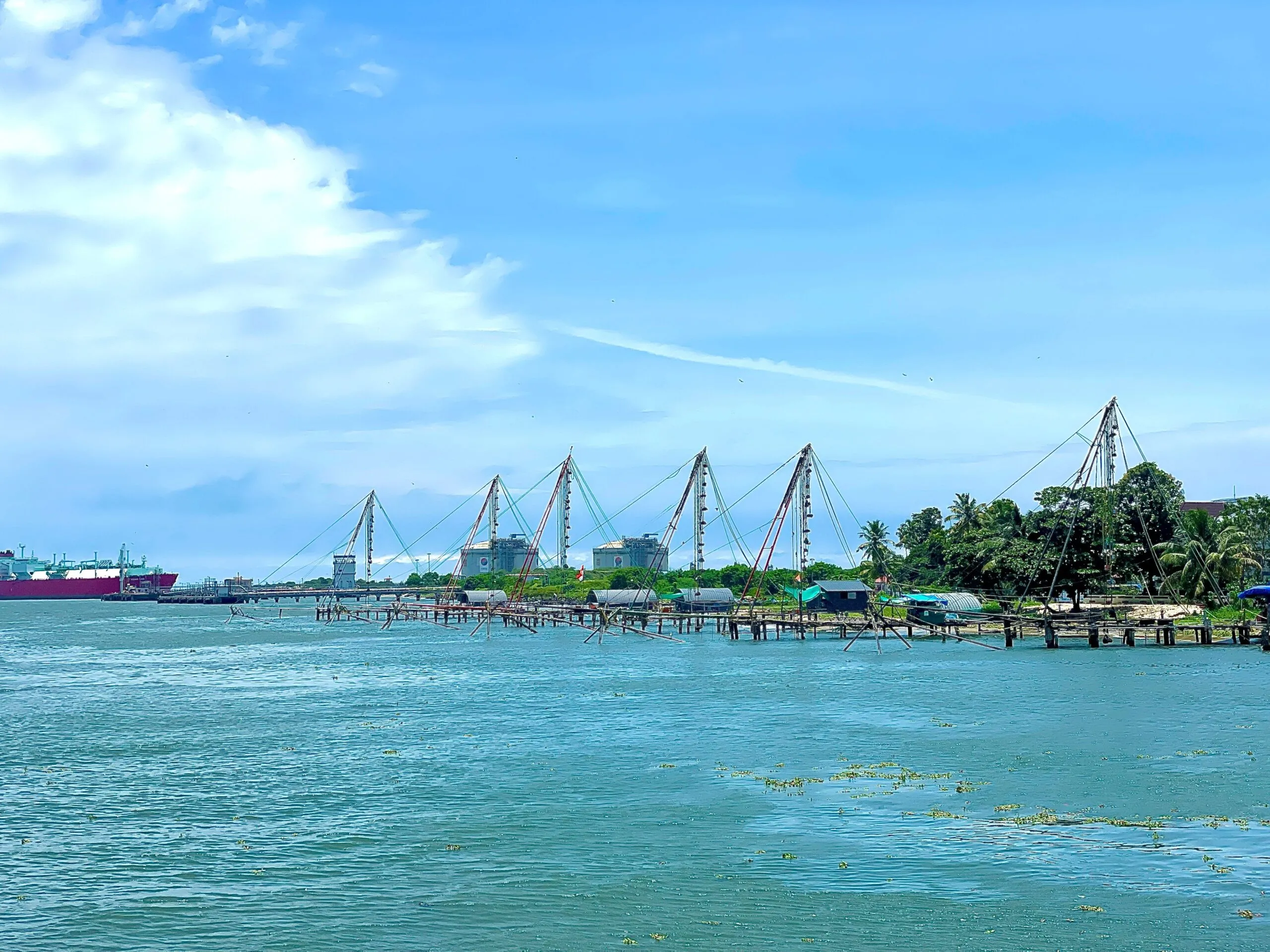 The image shows traditional Chinese fishing nets beside the waterfront at Fort Kochi.