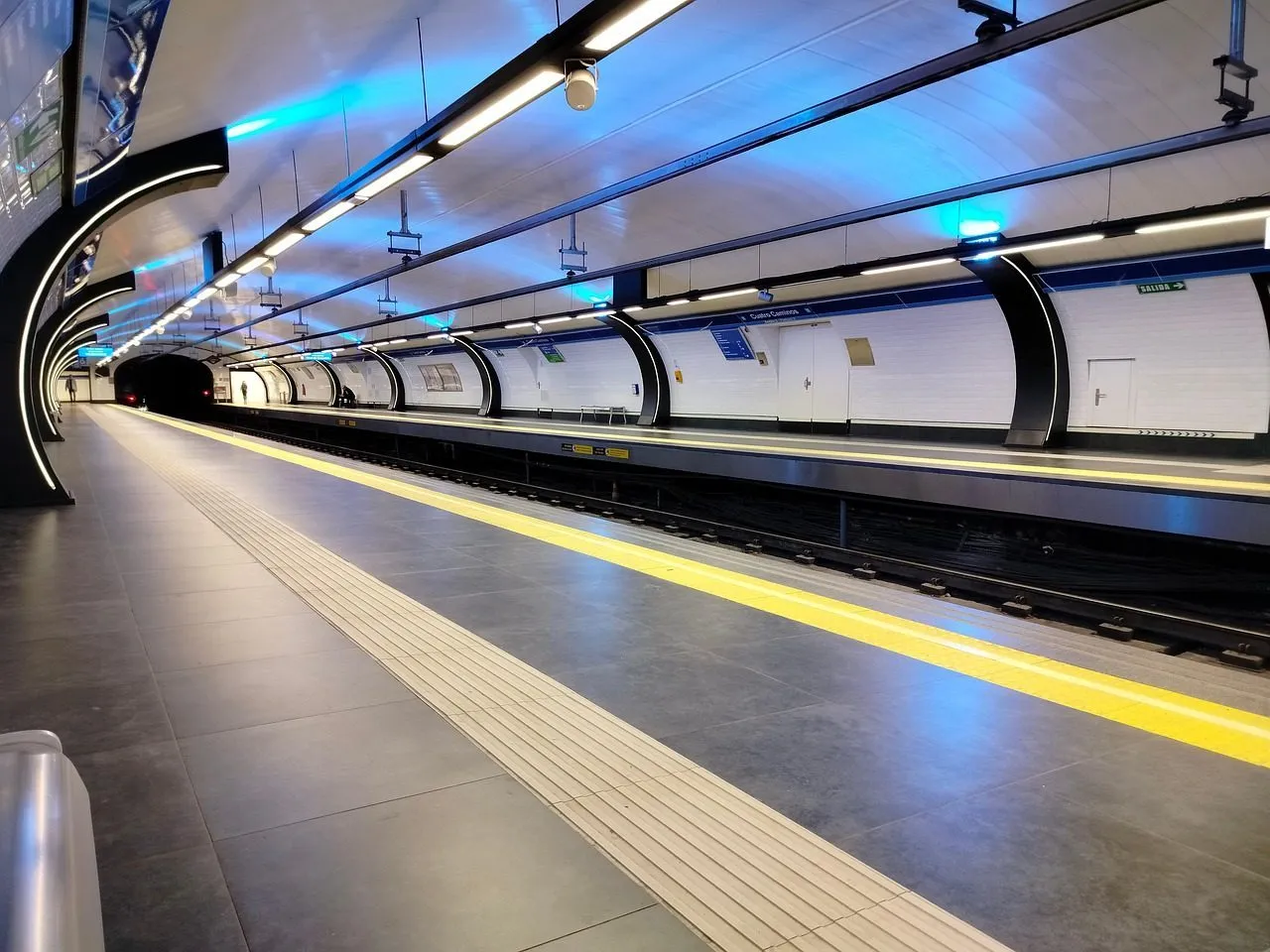 The image shows a modern Madrid Metro platform with a yellow safety marking.