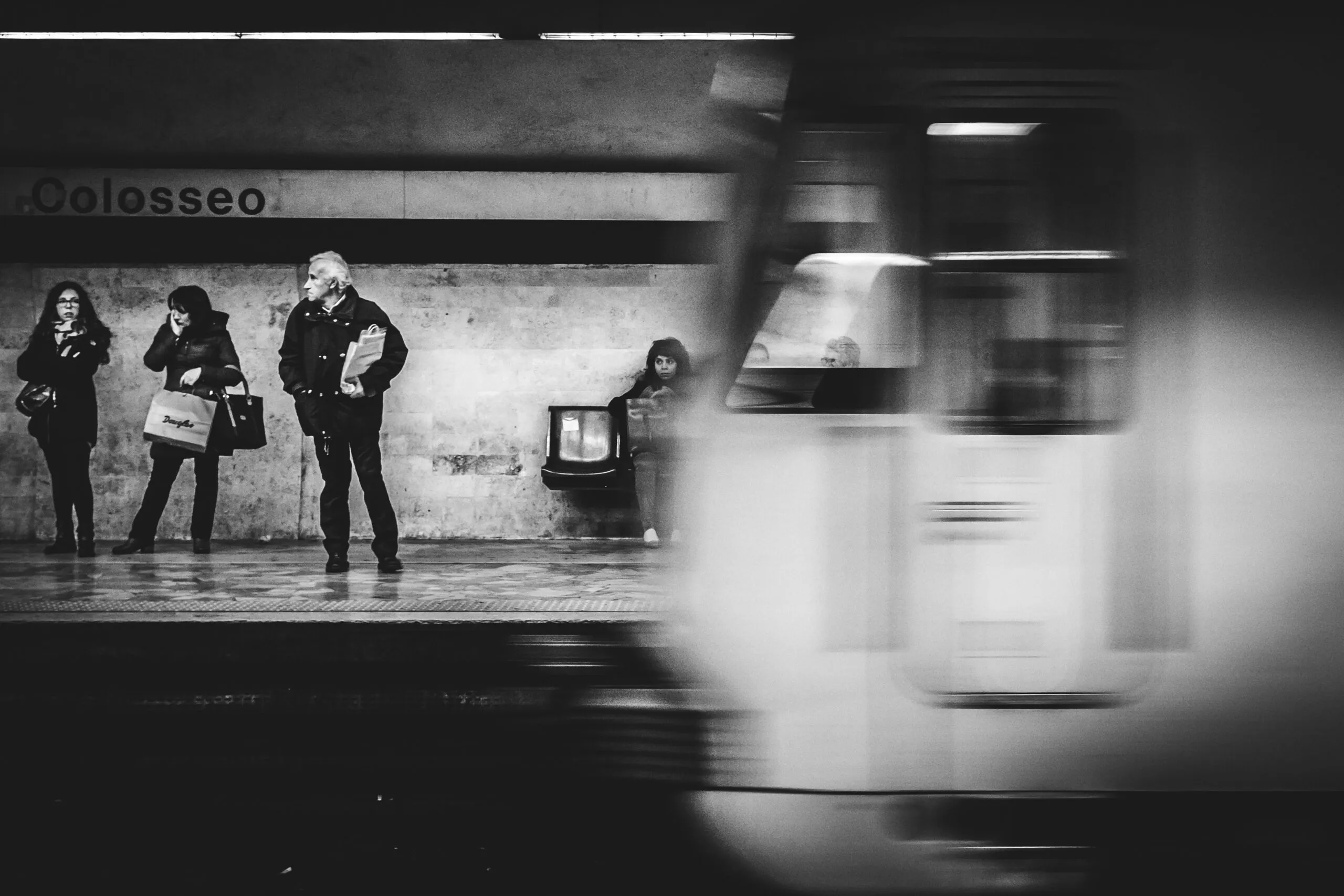 The image shows a Rome Metro train passing the Line B platform at Colosseo station.