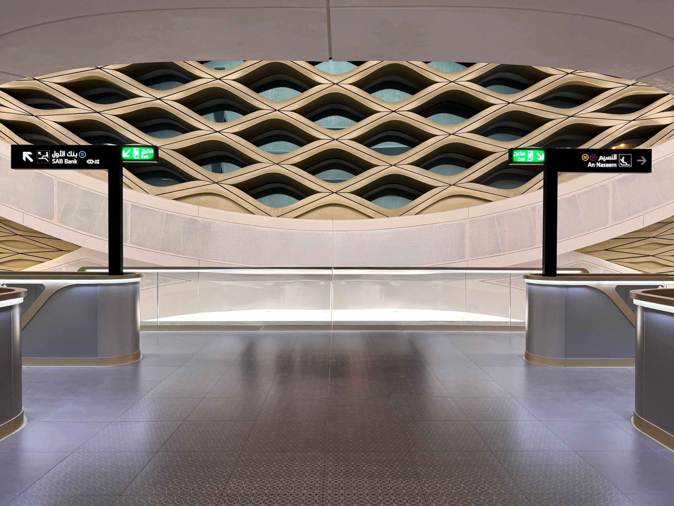 The image shows the modern interior of a Riyadh Metro station with signs pointing towards SAB Bank and An Naseem.