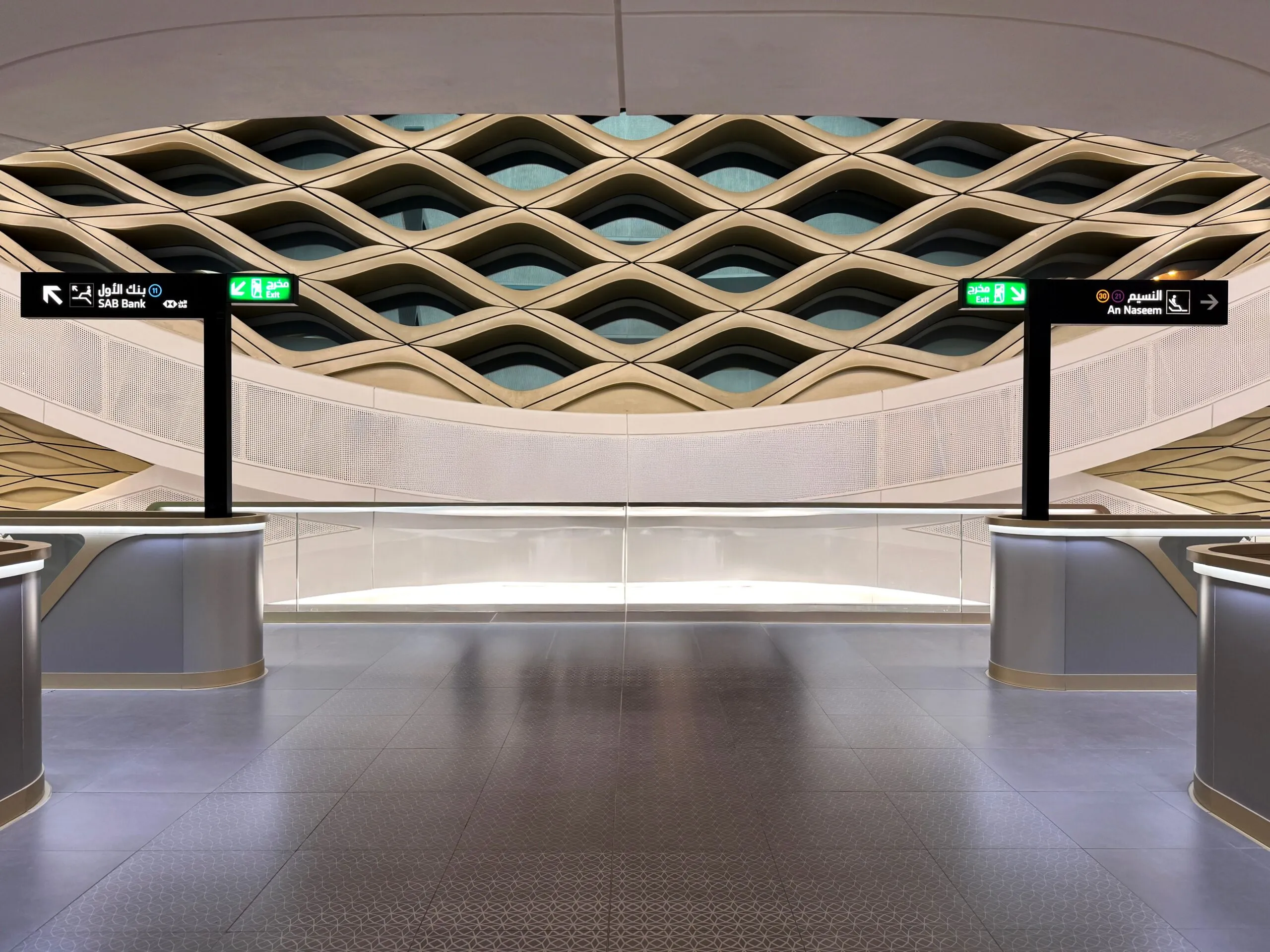 The image shows the modern interior of a Riyadh Metro station with signs pointing towards SAB Bank and An Naseem.