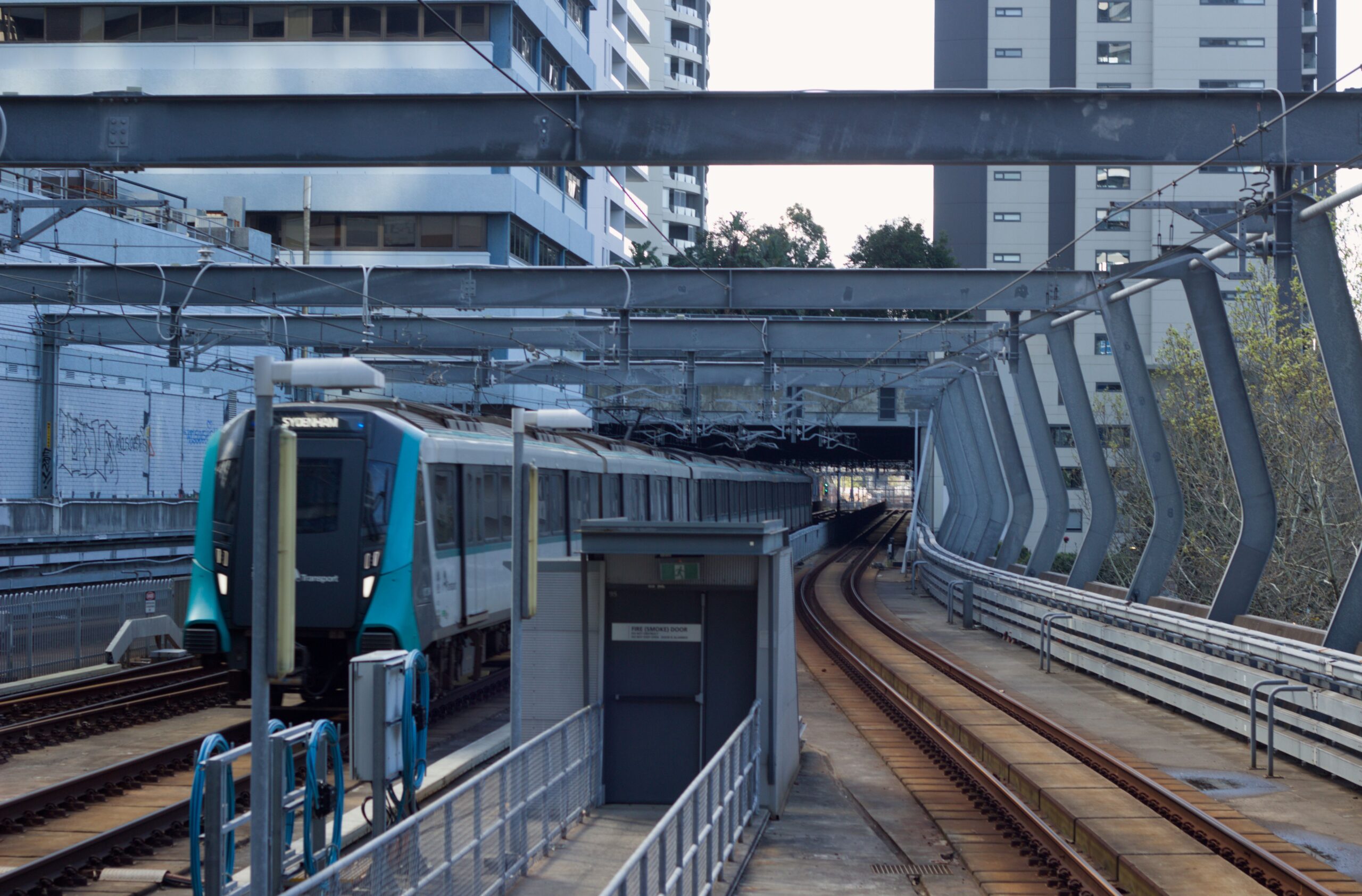 The image shows an M1 train approaching Chatswood station on the Sydney Metro network.
