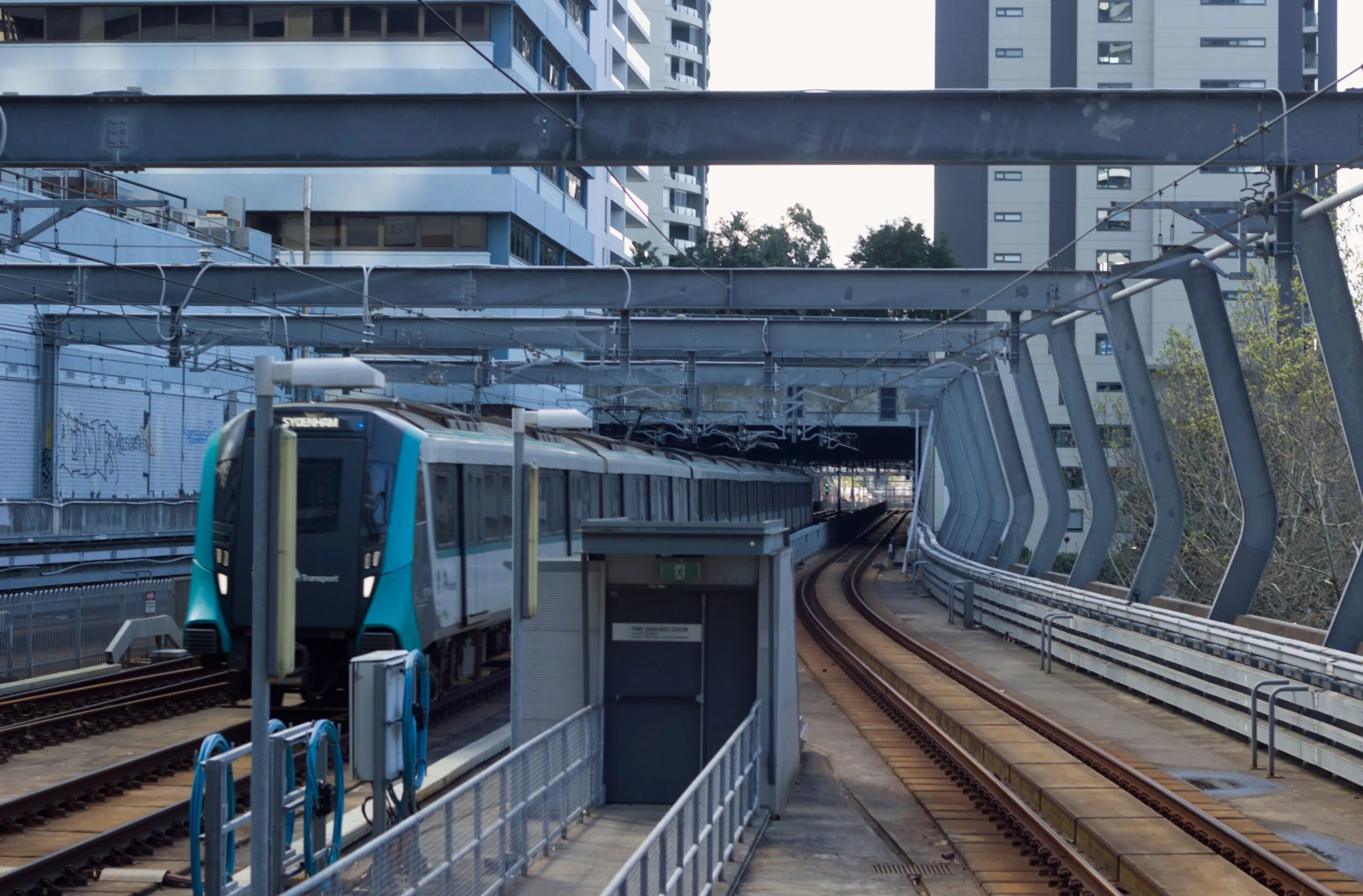 The image shows an M1 train approaching Chatswood station on the Sydney Metro network.