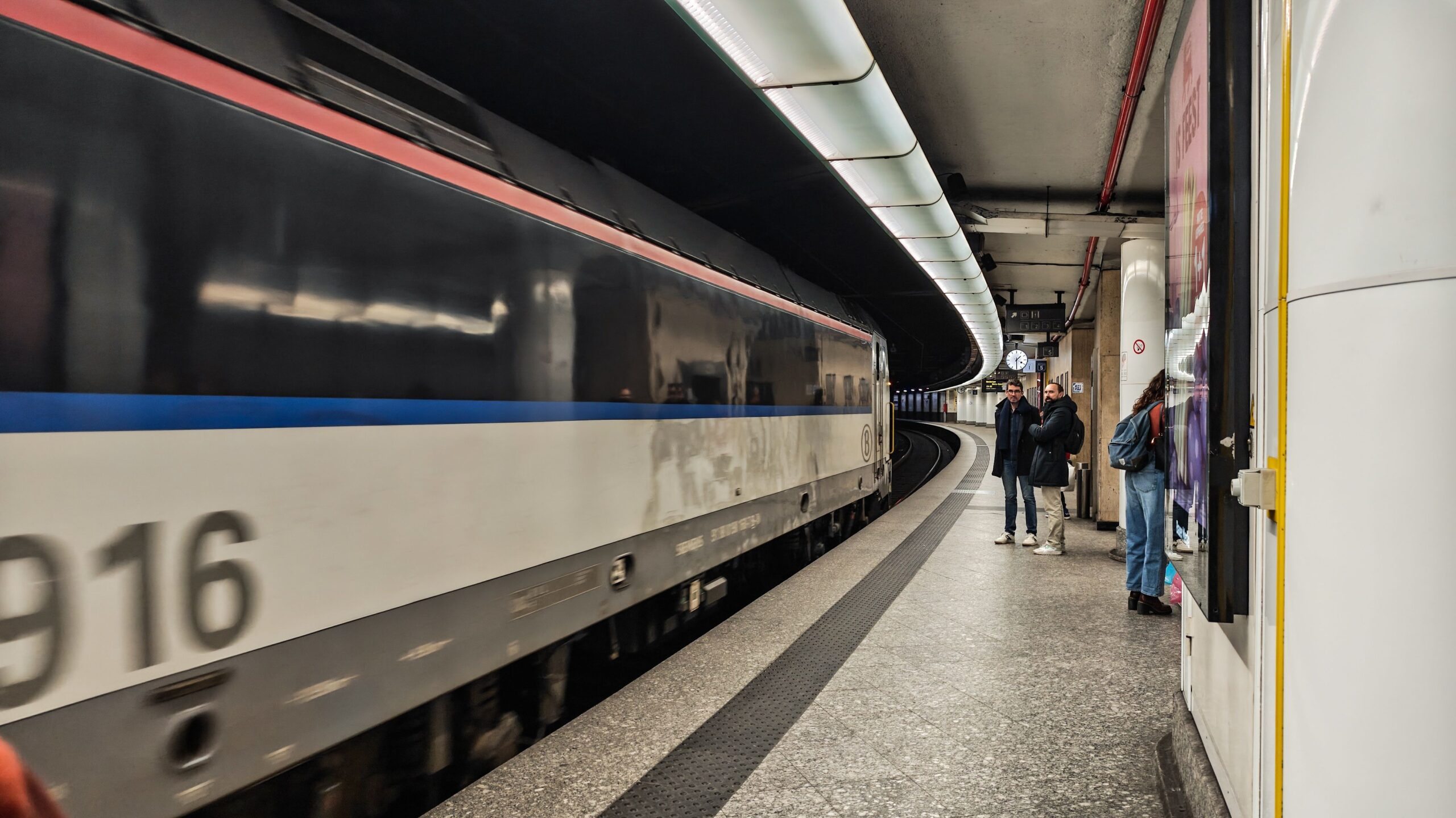 Auf dem Bild fährt ein Zug der Metro Brüssel in einen gebogenen unterirdischen Bahnsteig ein.