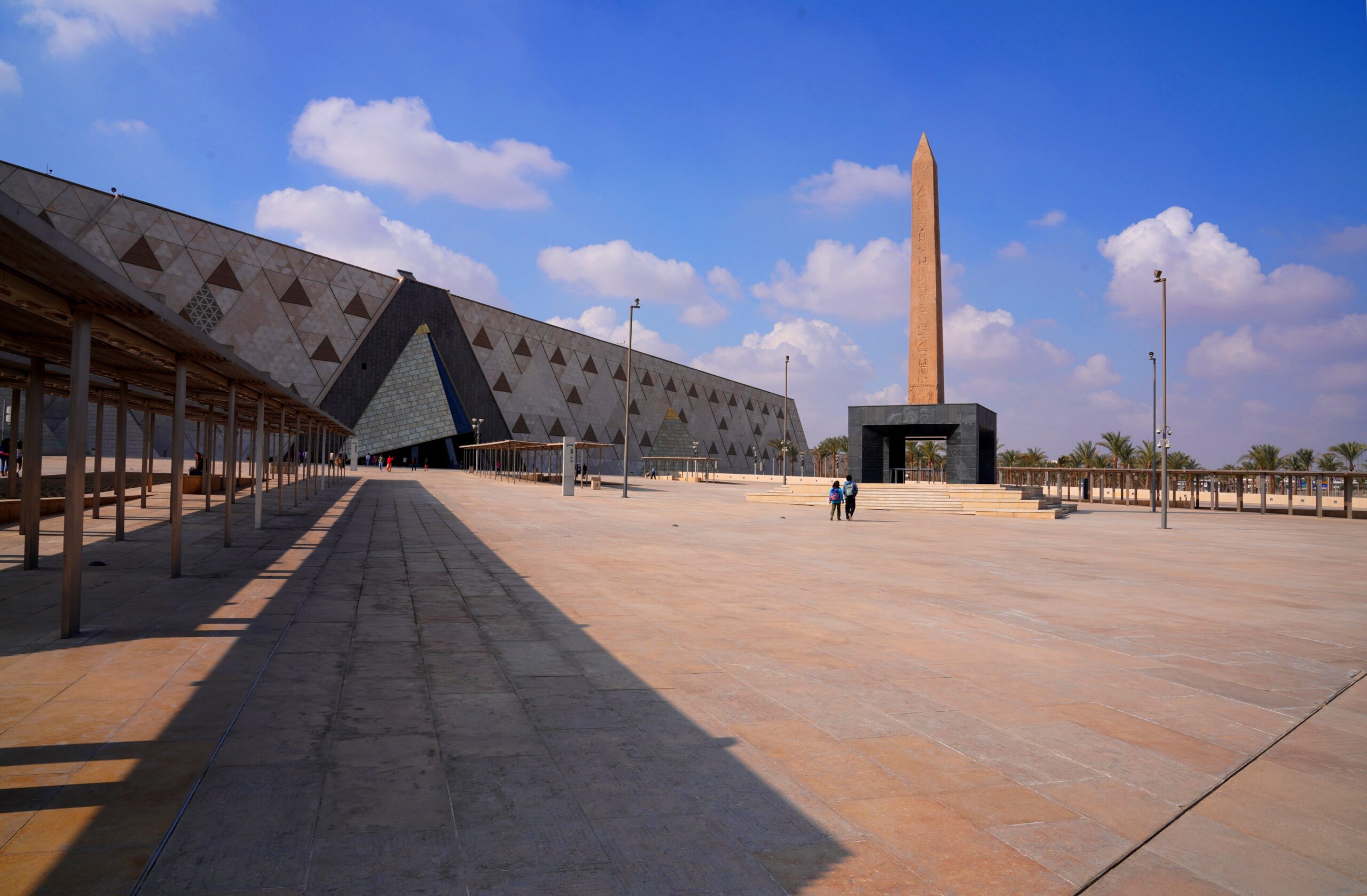 The Grand Egyptian Museum and its obelisk stand beneath a clear blue sky in Giza.