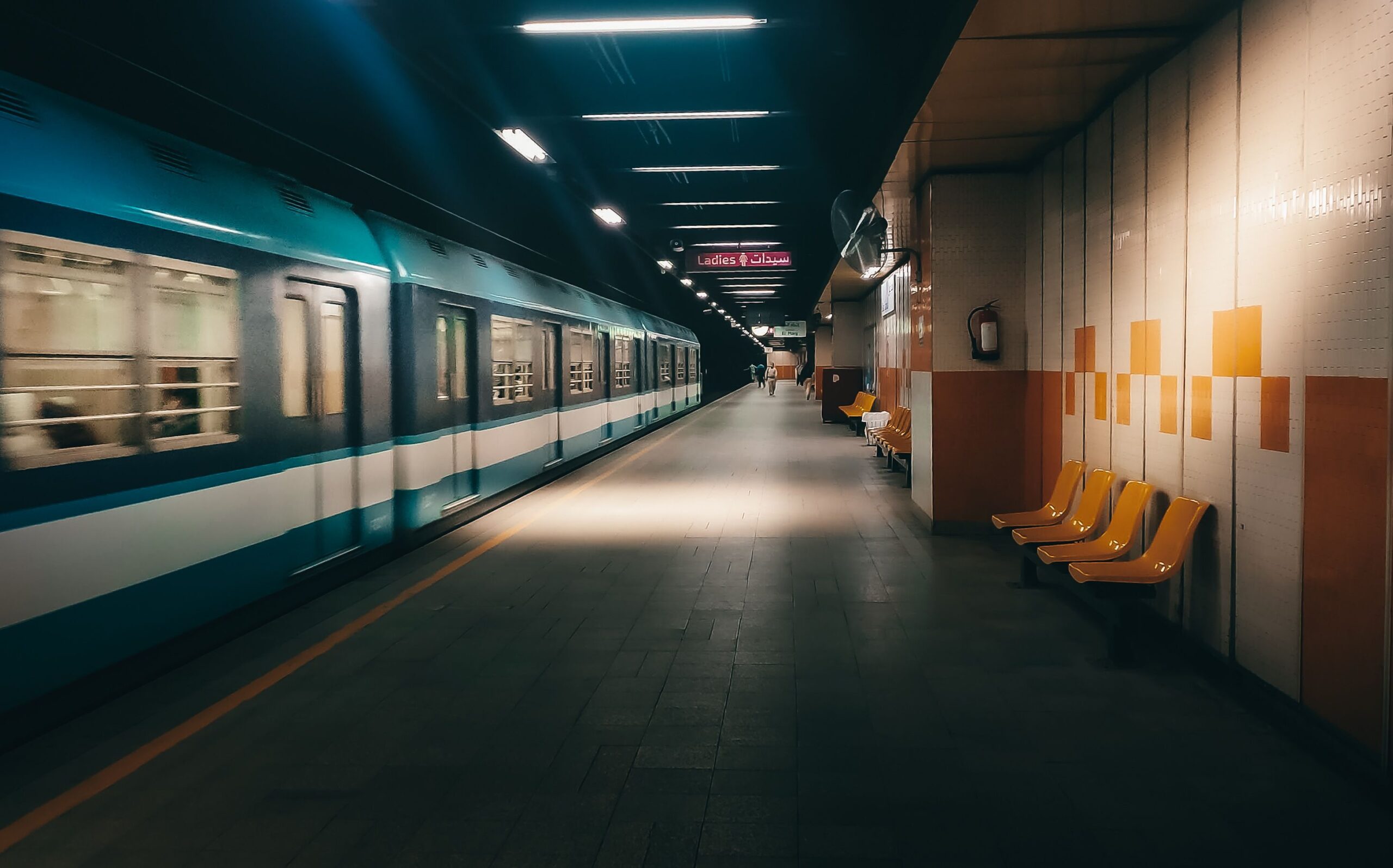 A Cairo Metro train passes an almost empty underground station platform.