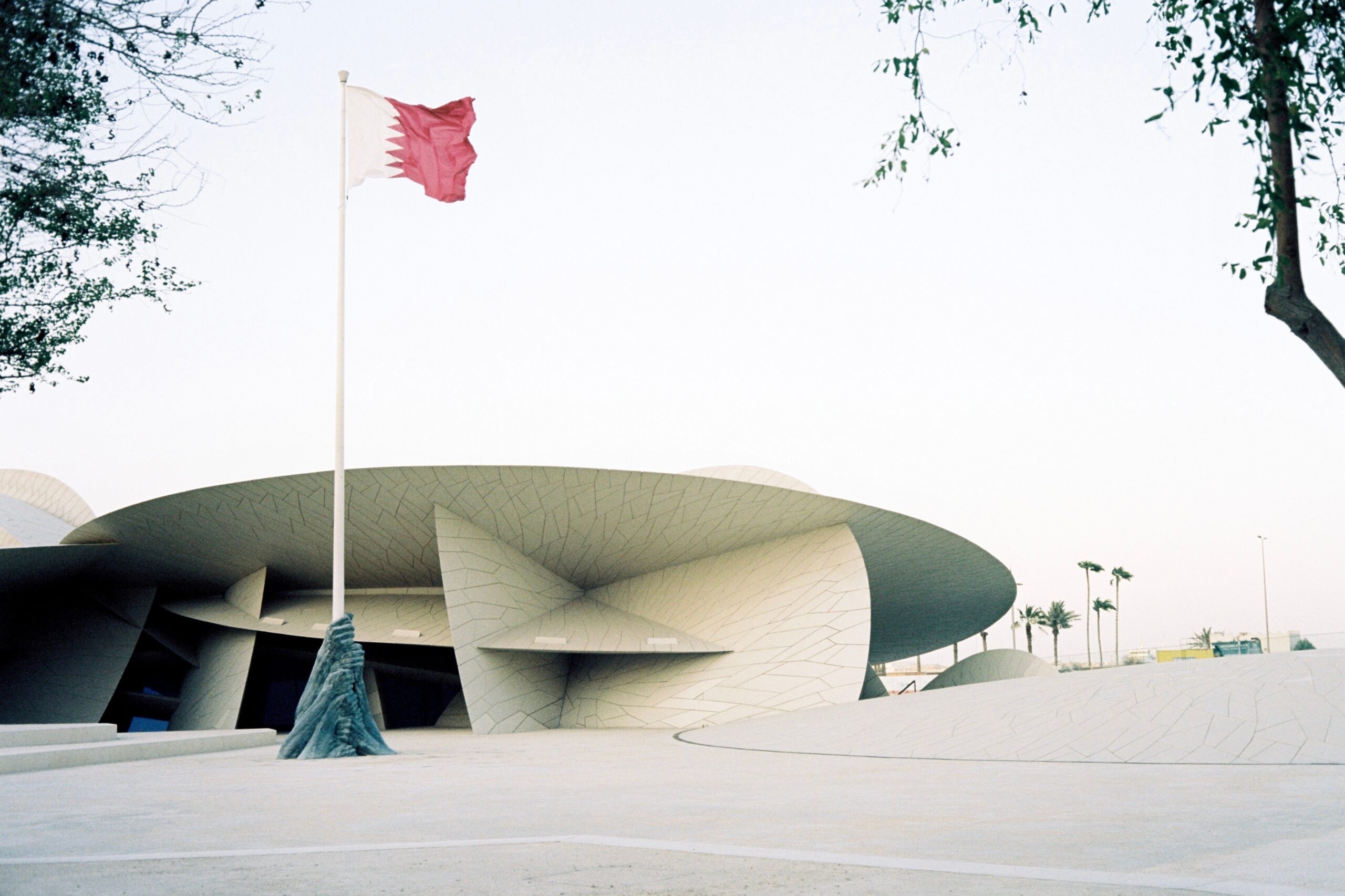Das National Museum of Qatar steht neben der katarischen Flagge in Doha.