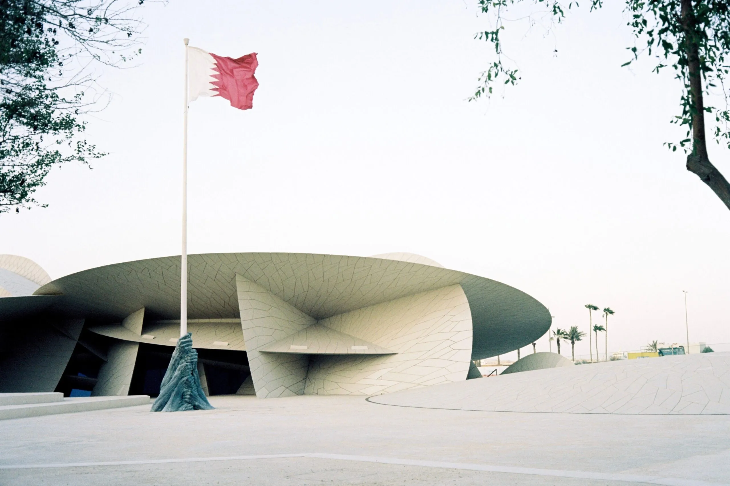 Das National Museum of Qatar steht neben der katarischen Flagge in Doha.