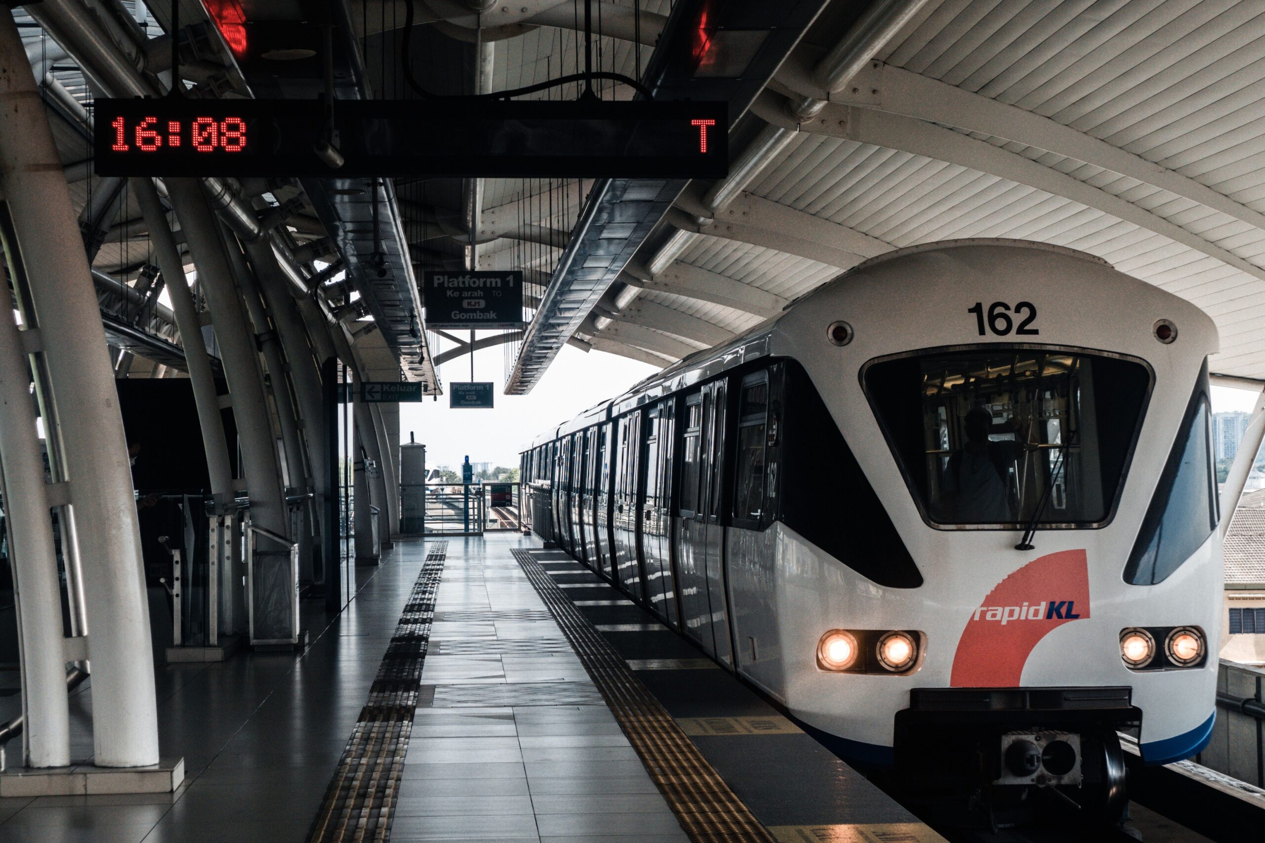The image shows a Rapid KL train waiting at an elevated station in Kuala Lumpur.