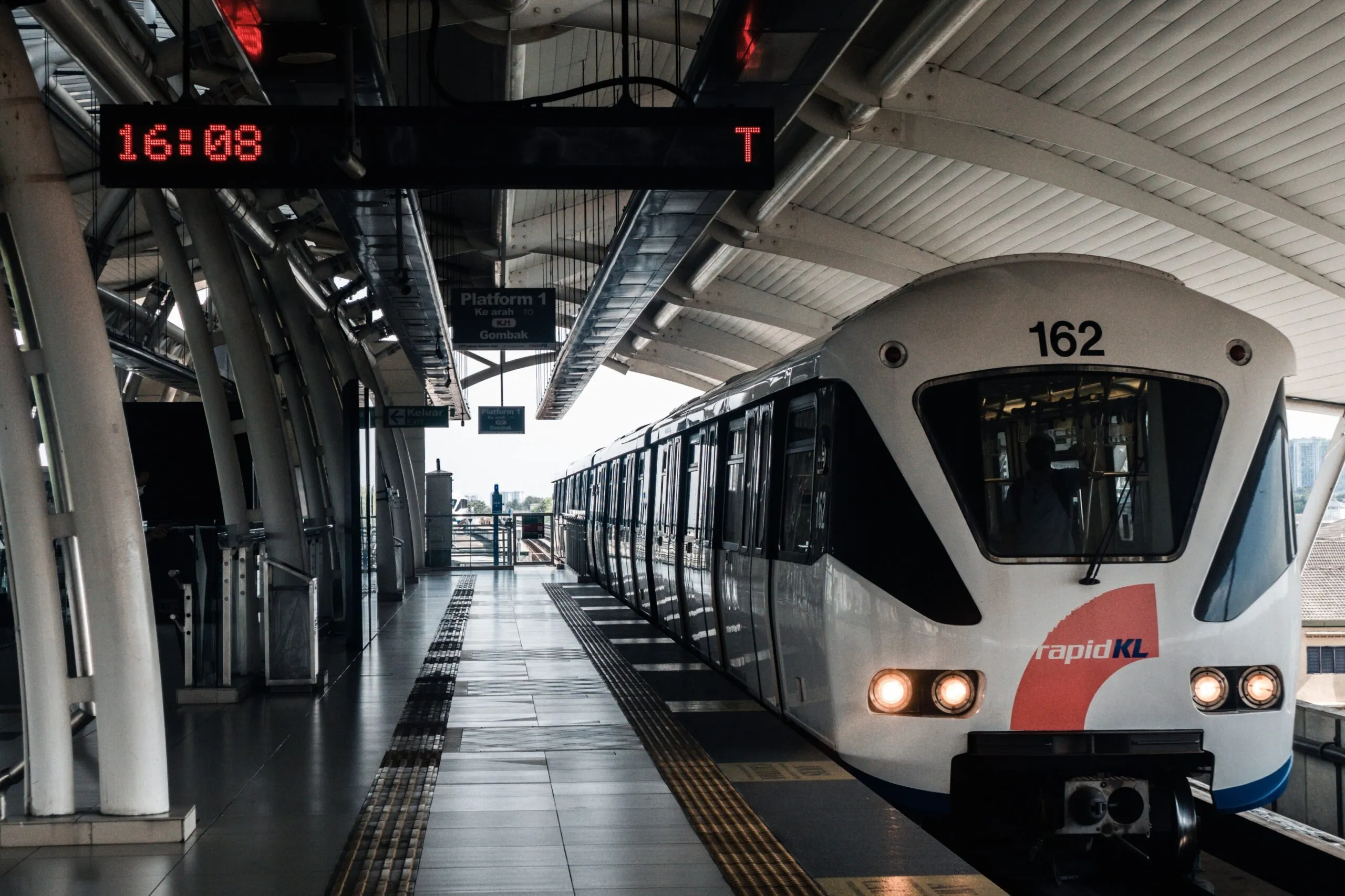 The image shows a Rapid KL train waiting at an elevated station in Kuala Lumpur.