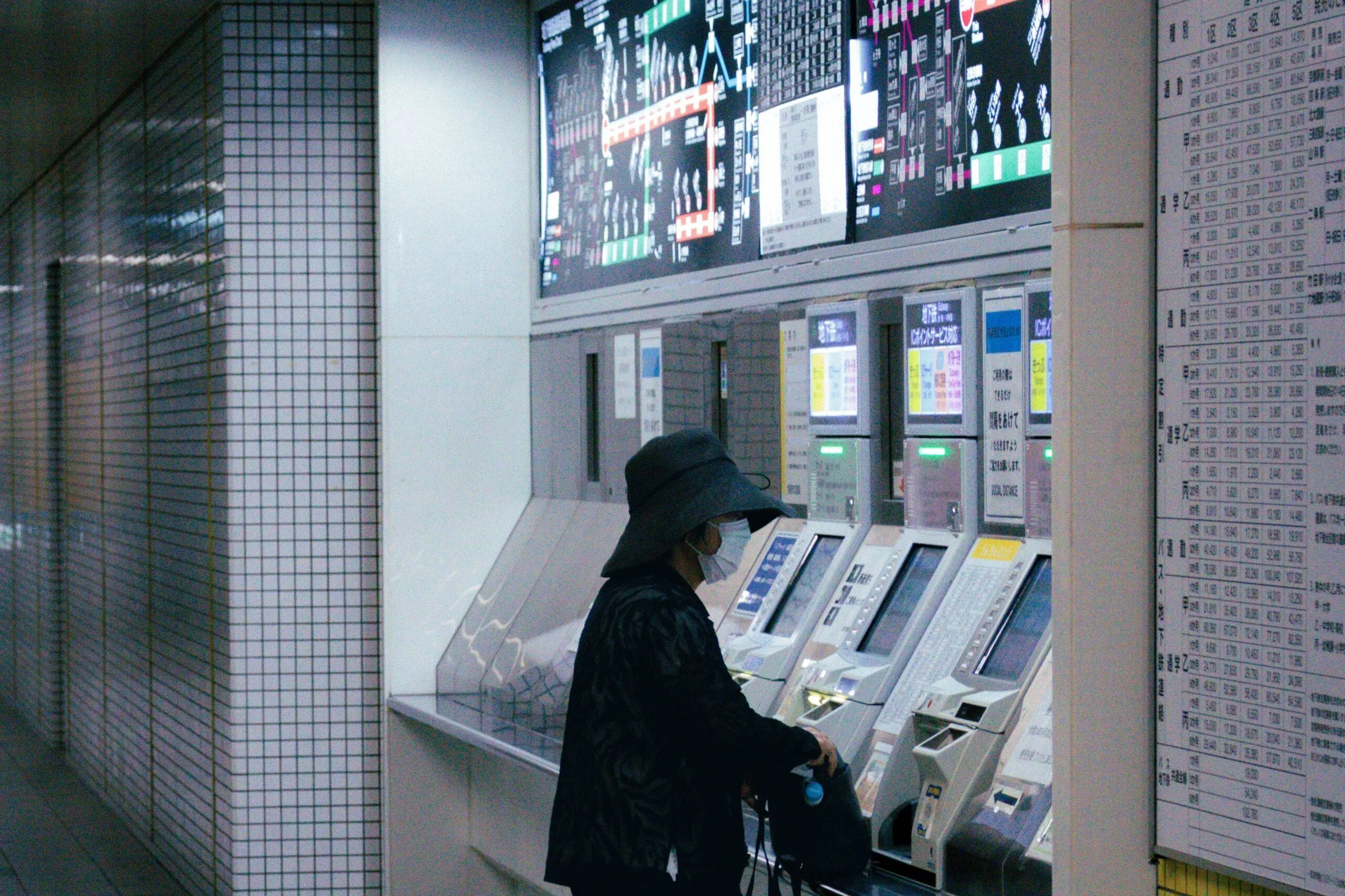 The image shows a traveler buying a ticket at the machines in a Kyoto underground station.