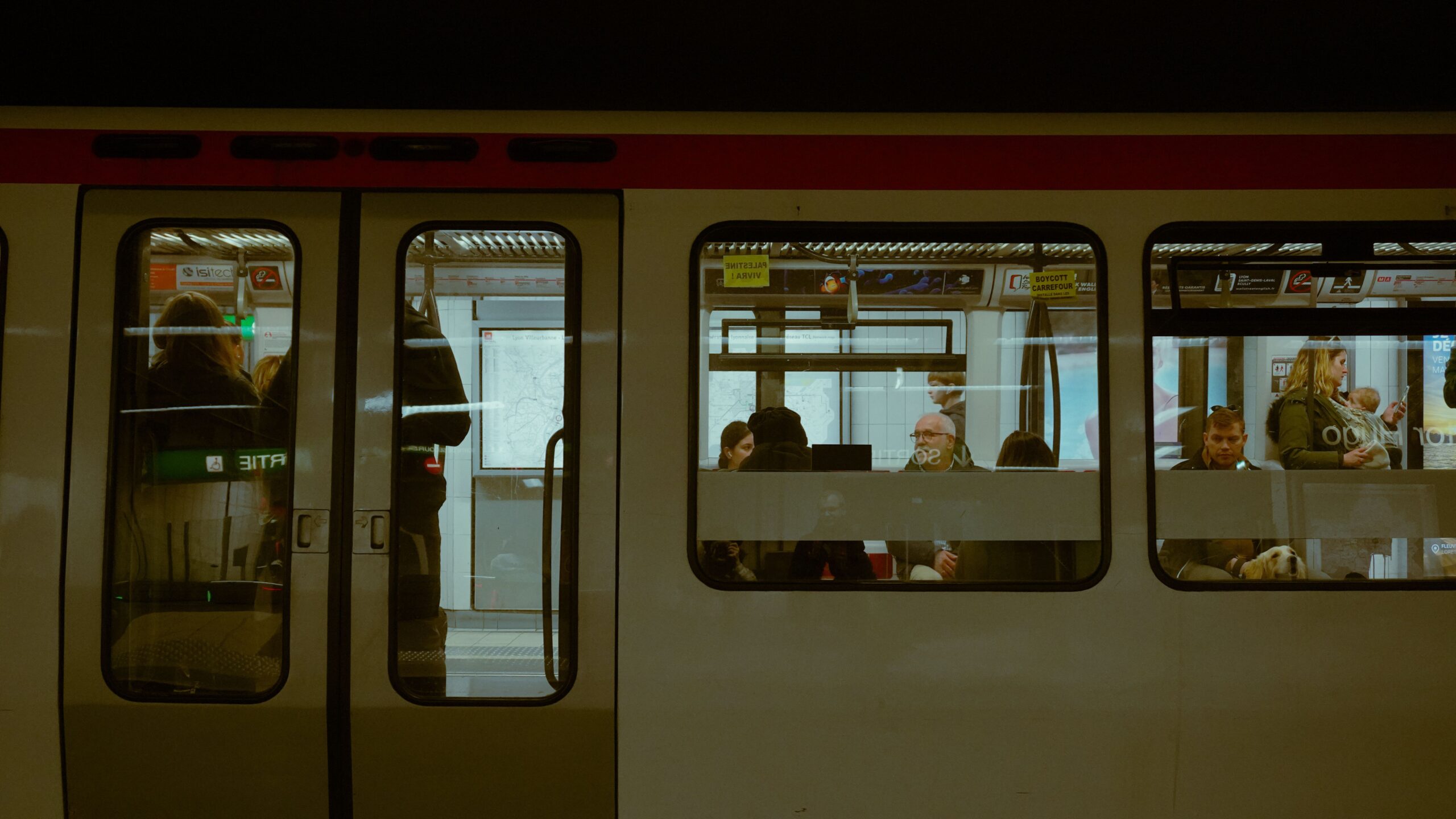 Ein Zug der Metro Lyon steht an einem Bahnsteig, während Fahrgäste durch die Fenster zu sehen sind.