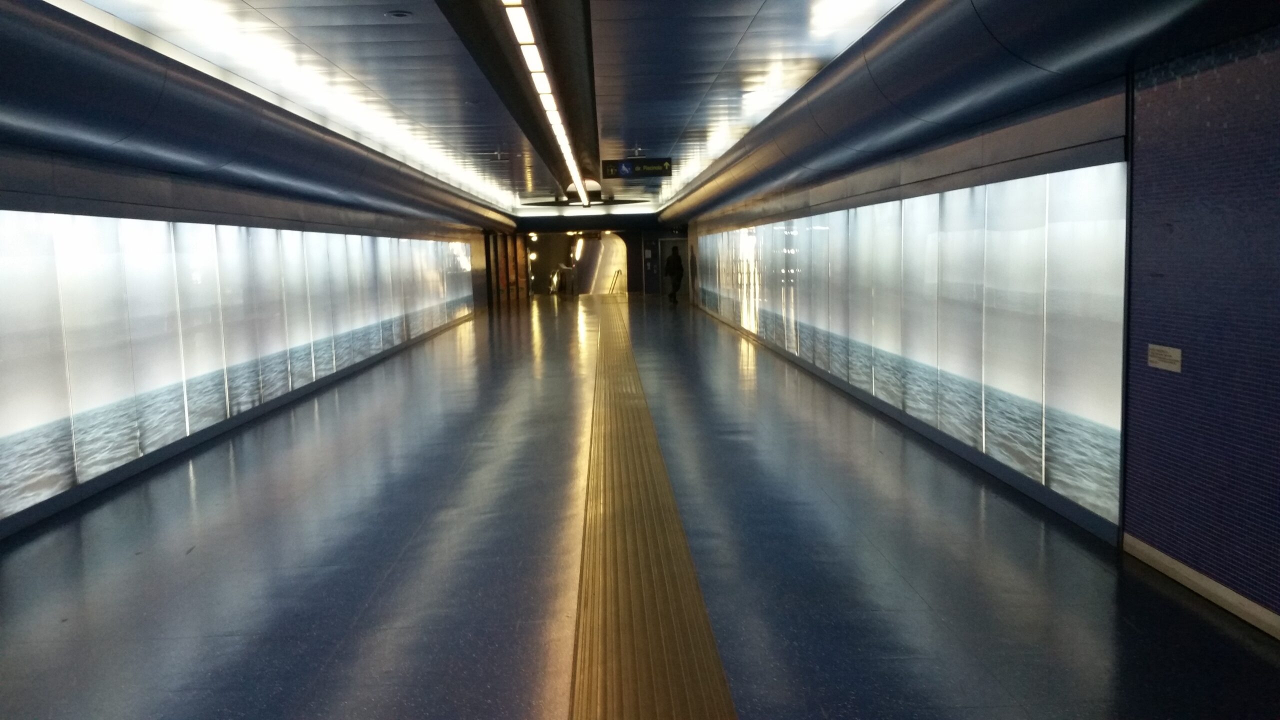Auf dem Bild ist ein beleuchteter Durchgang in einer Metrostation in Neapel zu sehen.