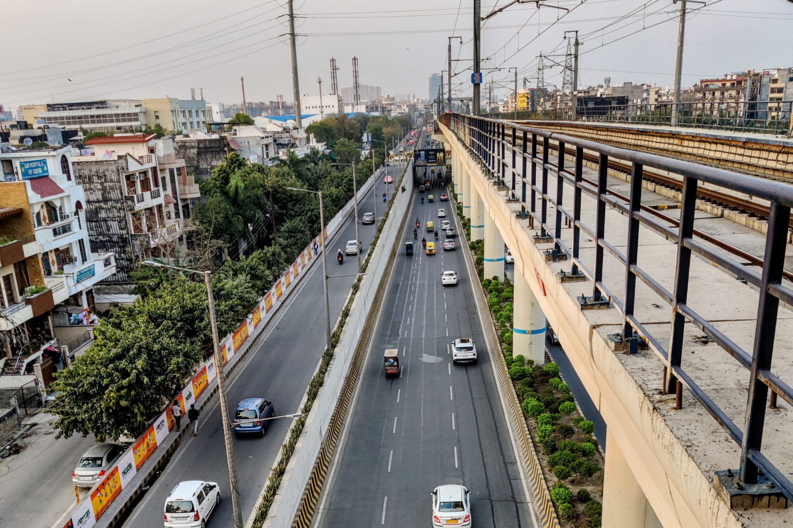 Eine erhöhte Bahntrasse verläuft in Noida neben einer mehrspurigen Straße.