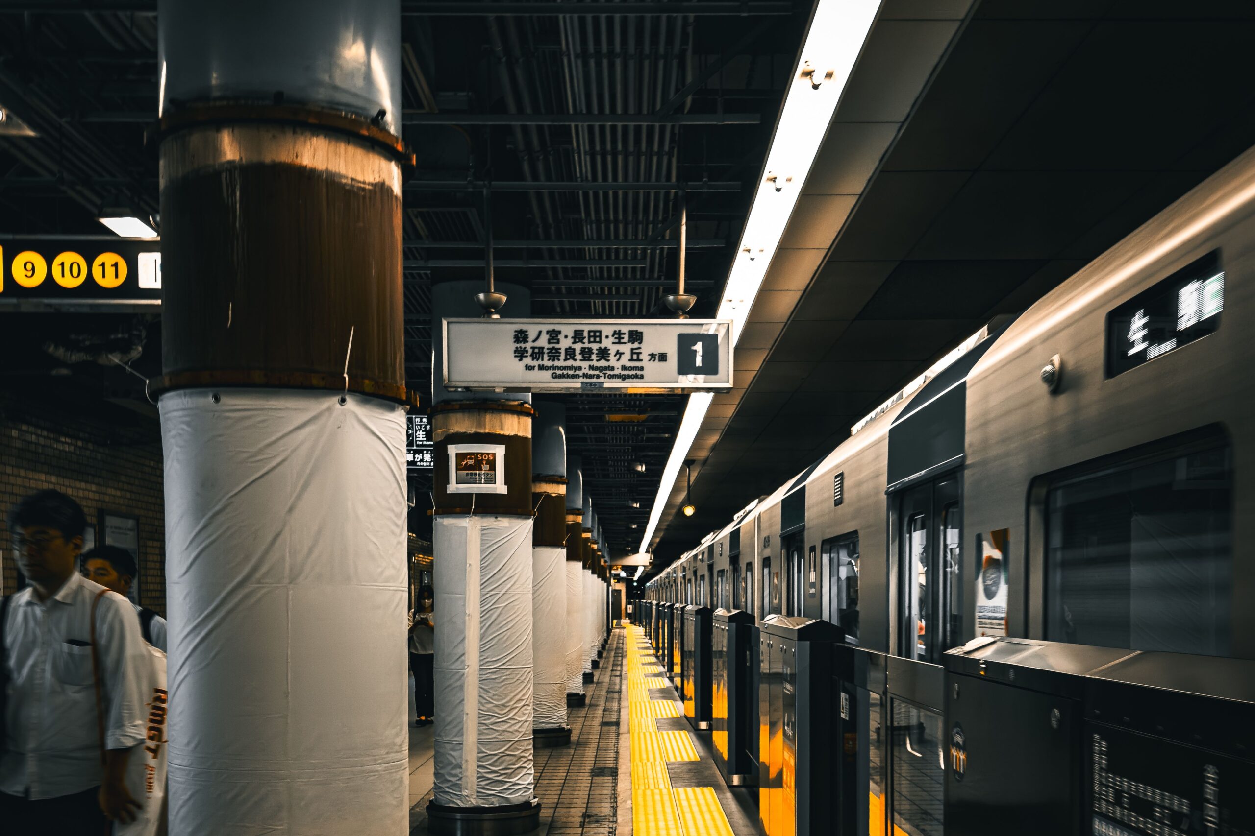 Ein Zug der Osaka Metro steht an einem Bahnsteig mit Wegweisern nach Morinomiya und Nagata.