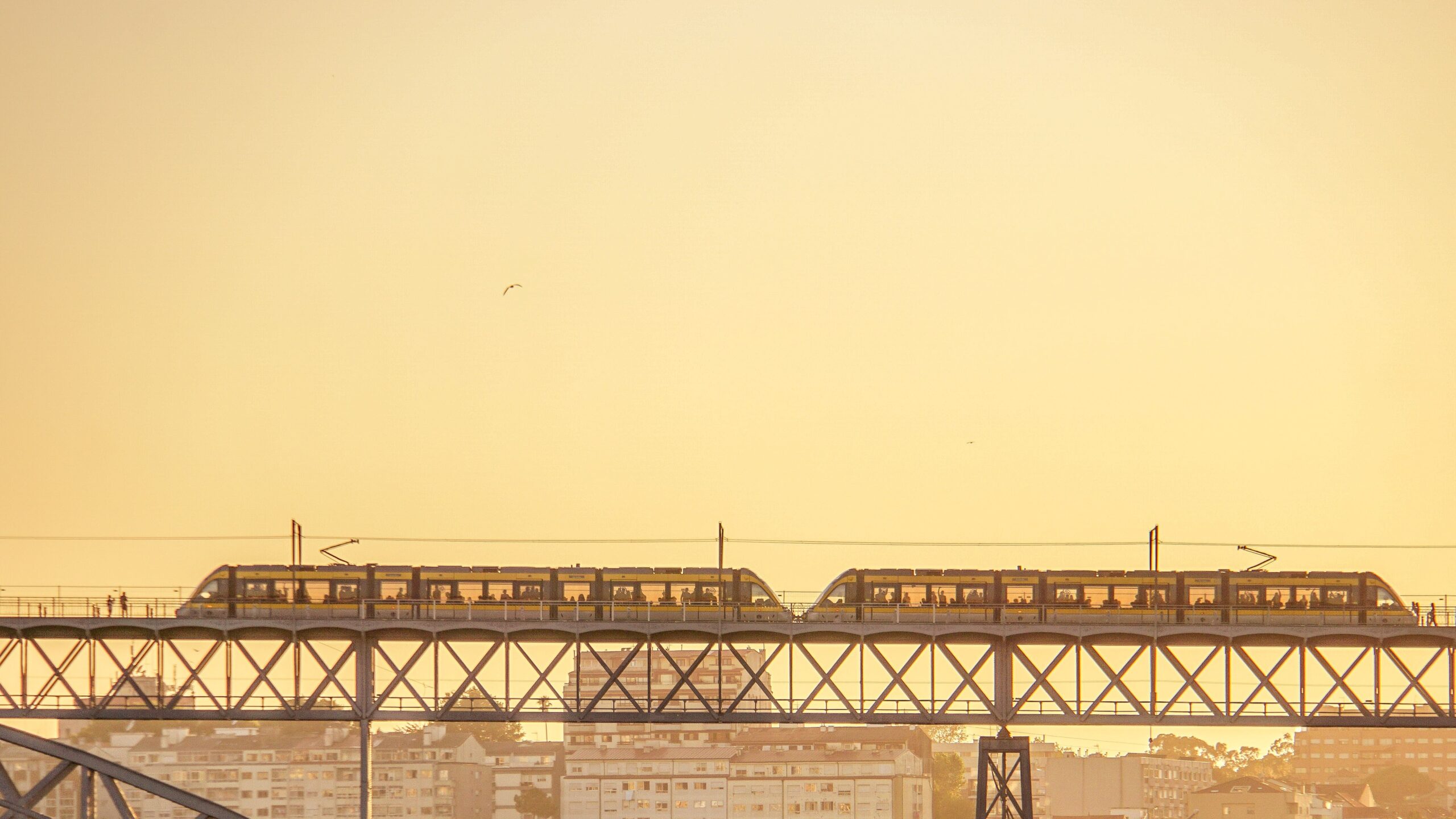 A Metro do Porto light-rail train crosses the upper level of Dom Luís I Bridge at sunset.