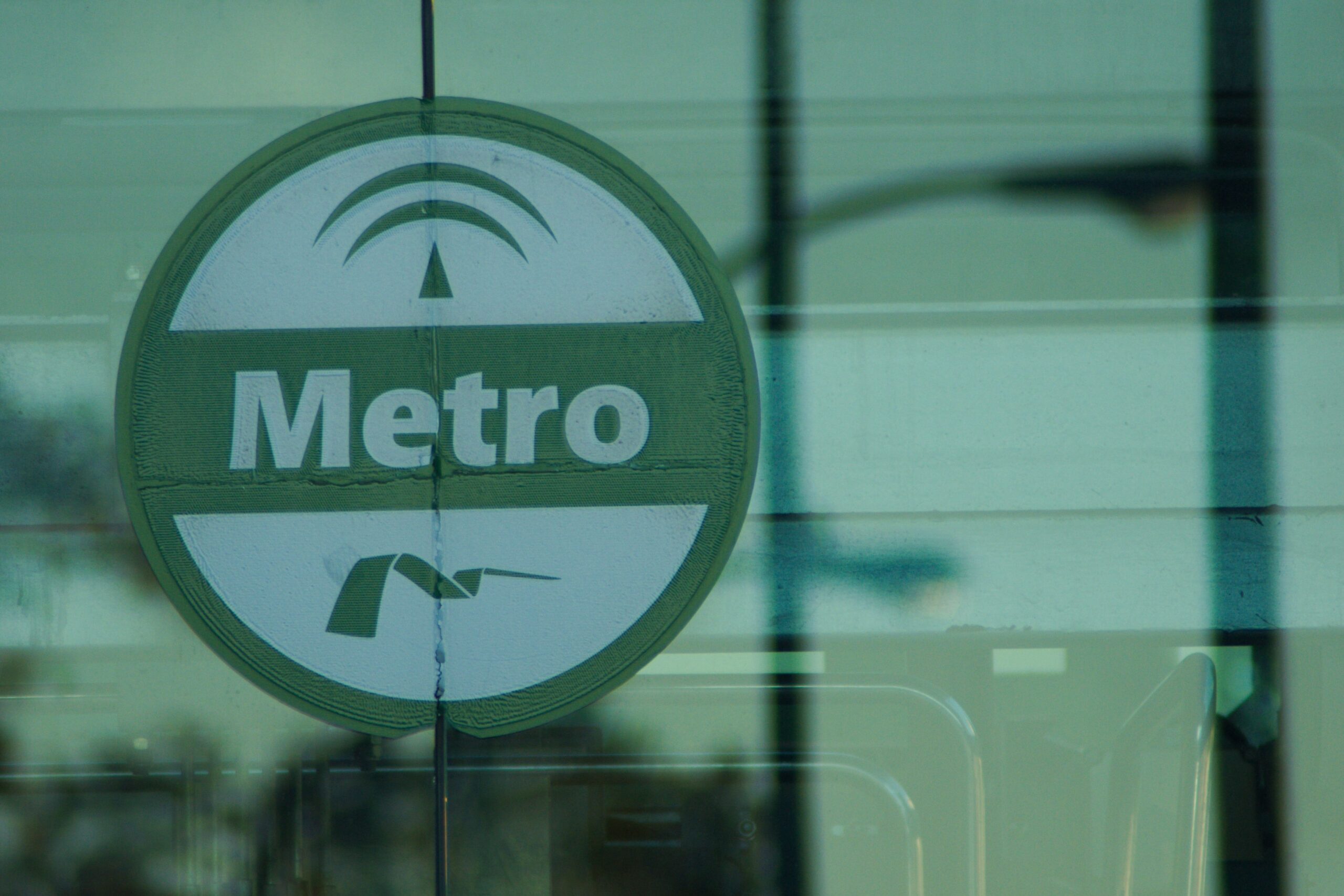 An einem gläsernen Eingang einer Stadtstation ist das Schild der Metro Sevilla zu sehen.