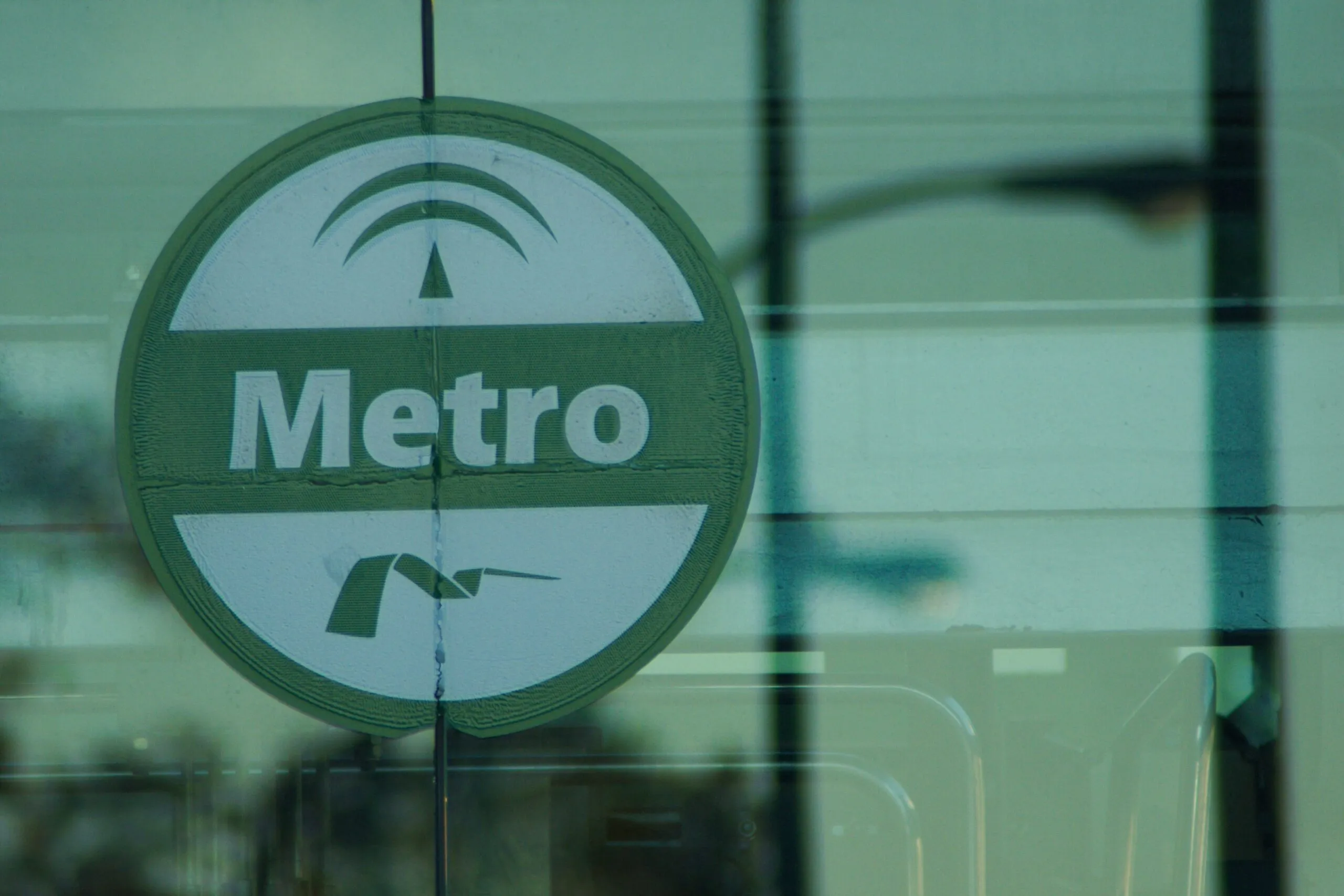 A Seville Metro sign appears on the glass entrance of an urban station.