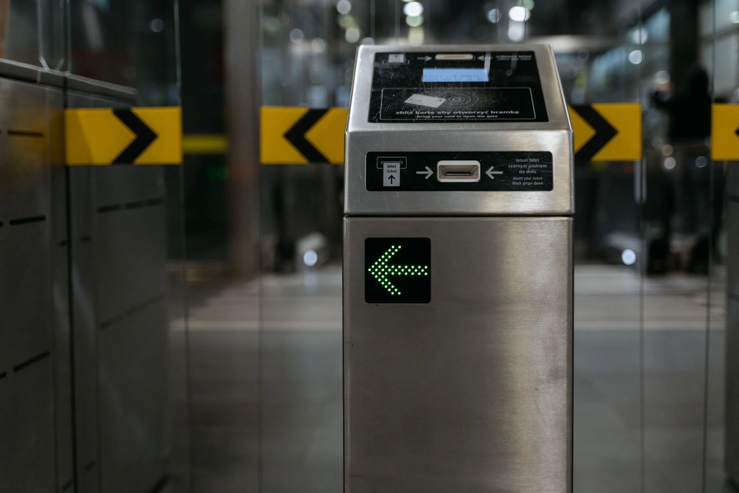 A contactless transit gate shows an illuminated arrow for ticket validation.