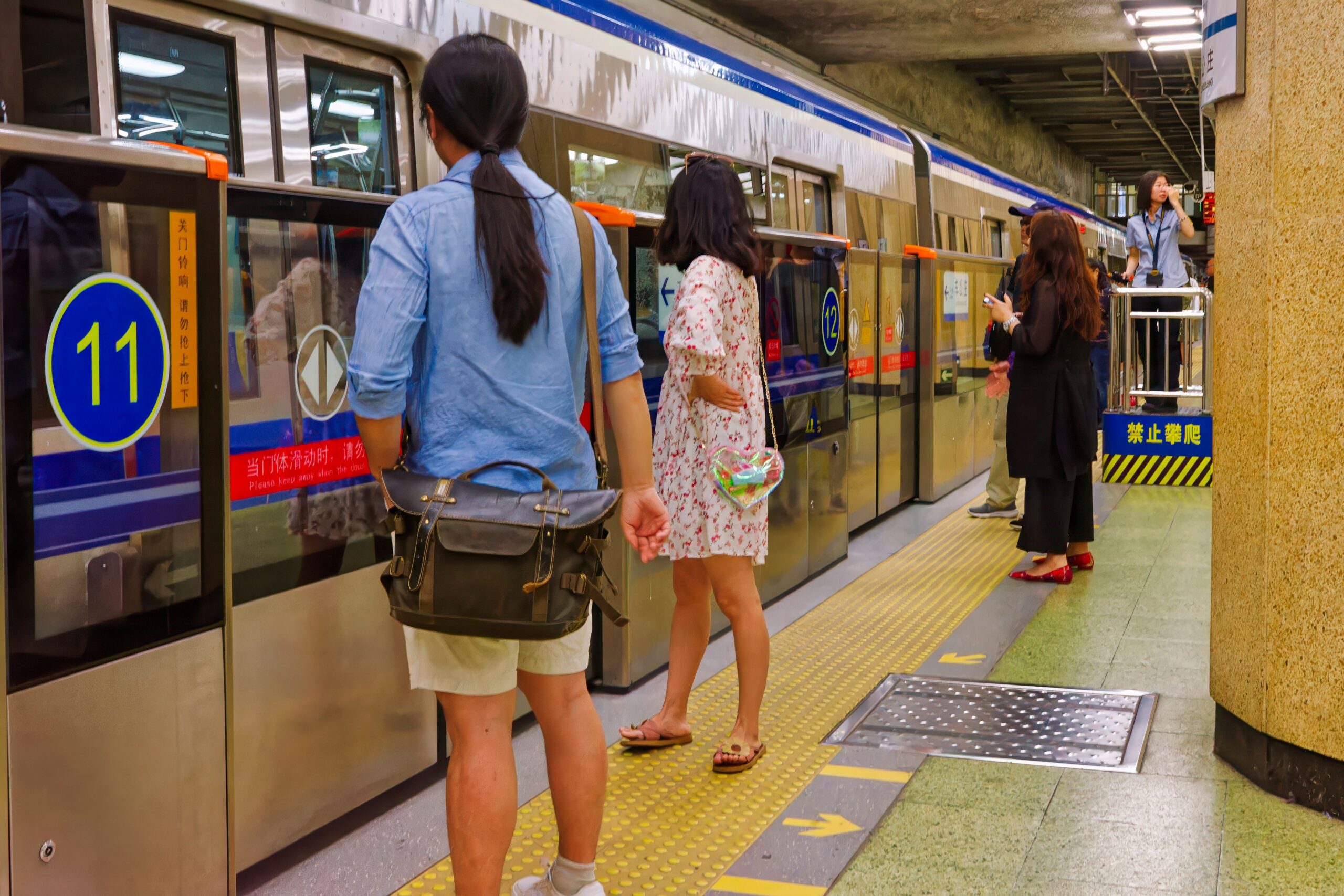 The image shows passengers waiting behind platform screen doors beside a subway train.