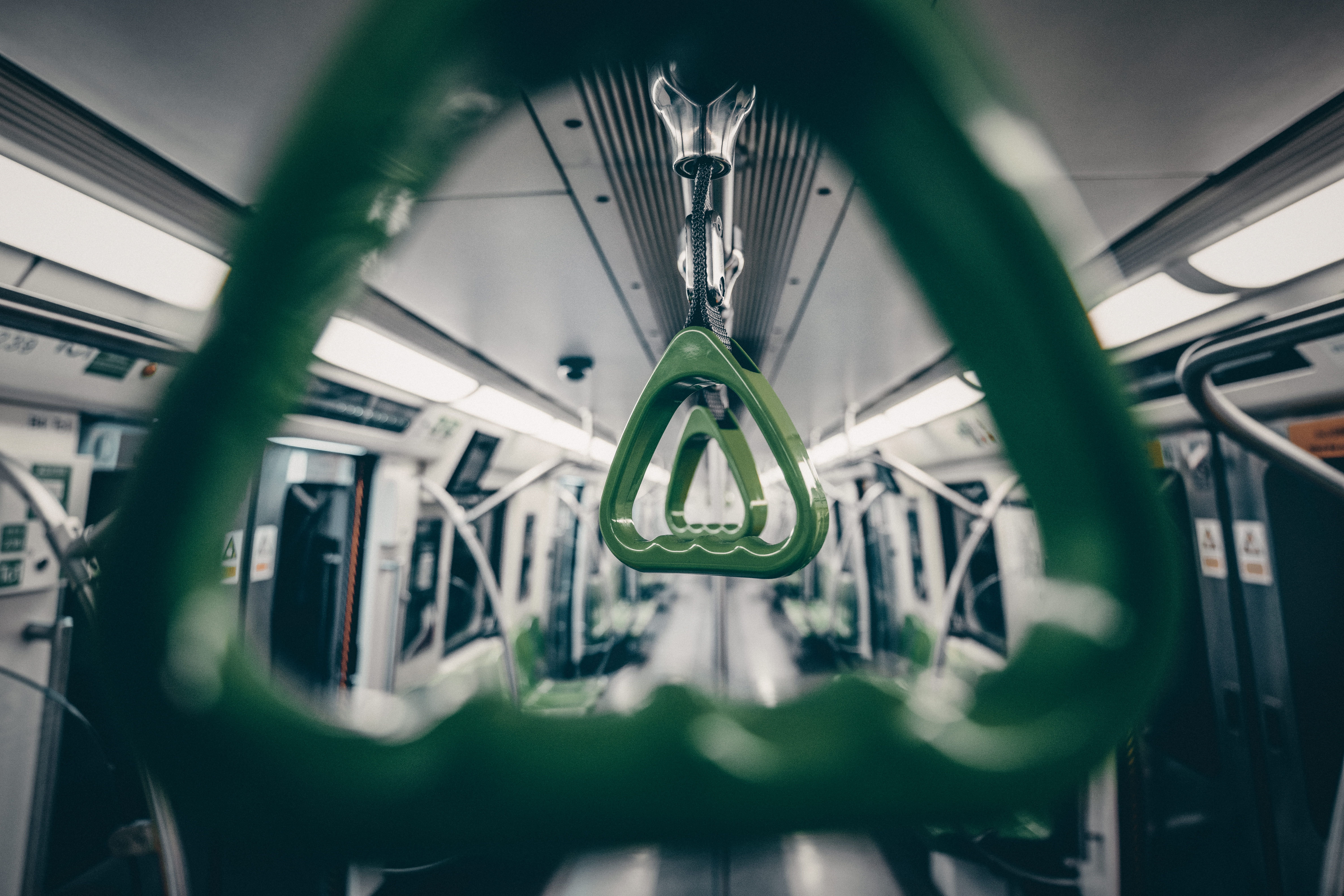 The image shows green hand straps inside an empty subway train.