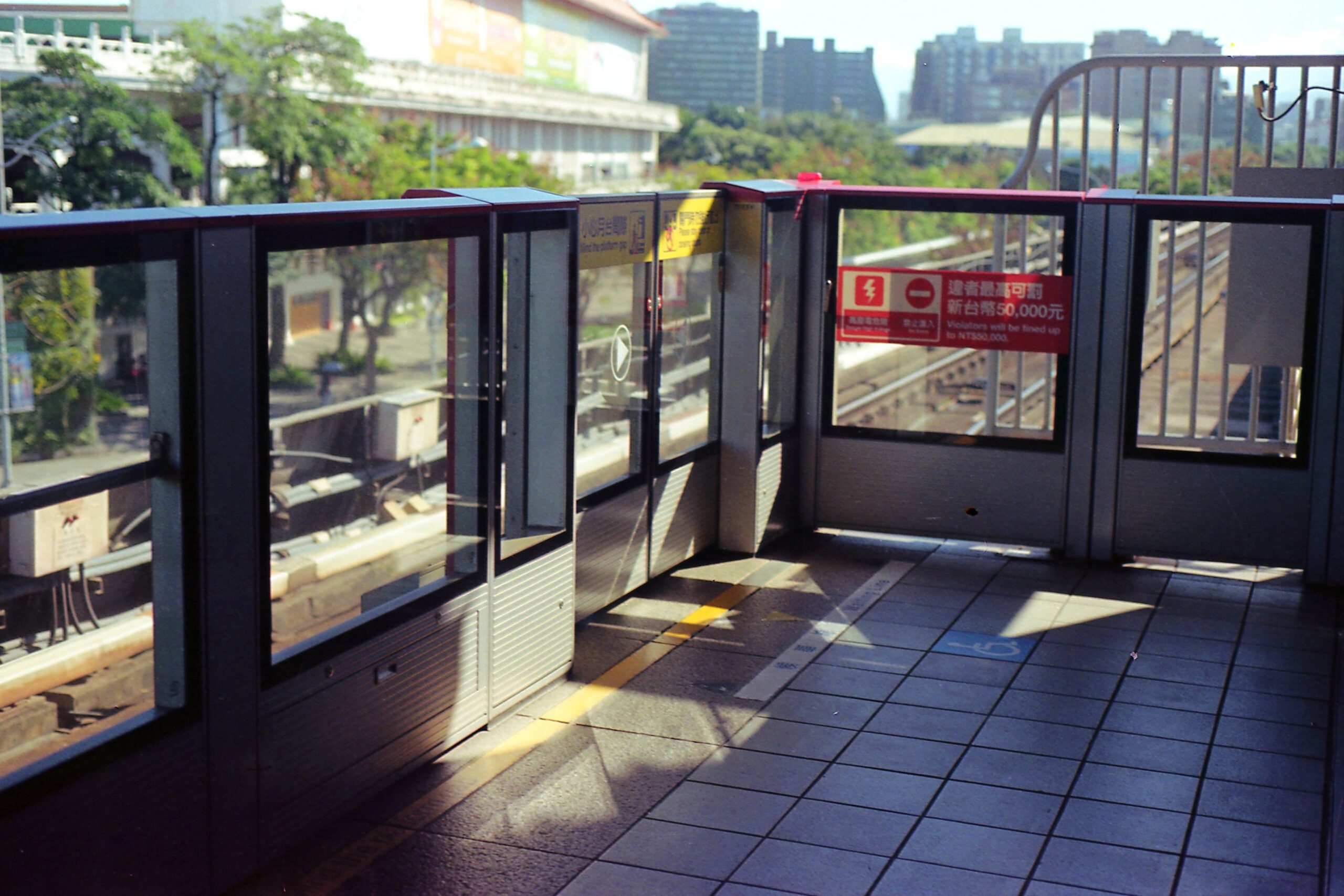 Ein sonniger Bahnsteig der Taipei Metro mit Bahnsteigtüren verläuft parallel zu den Gleisen.