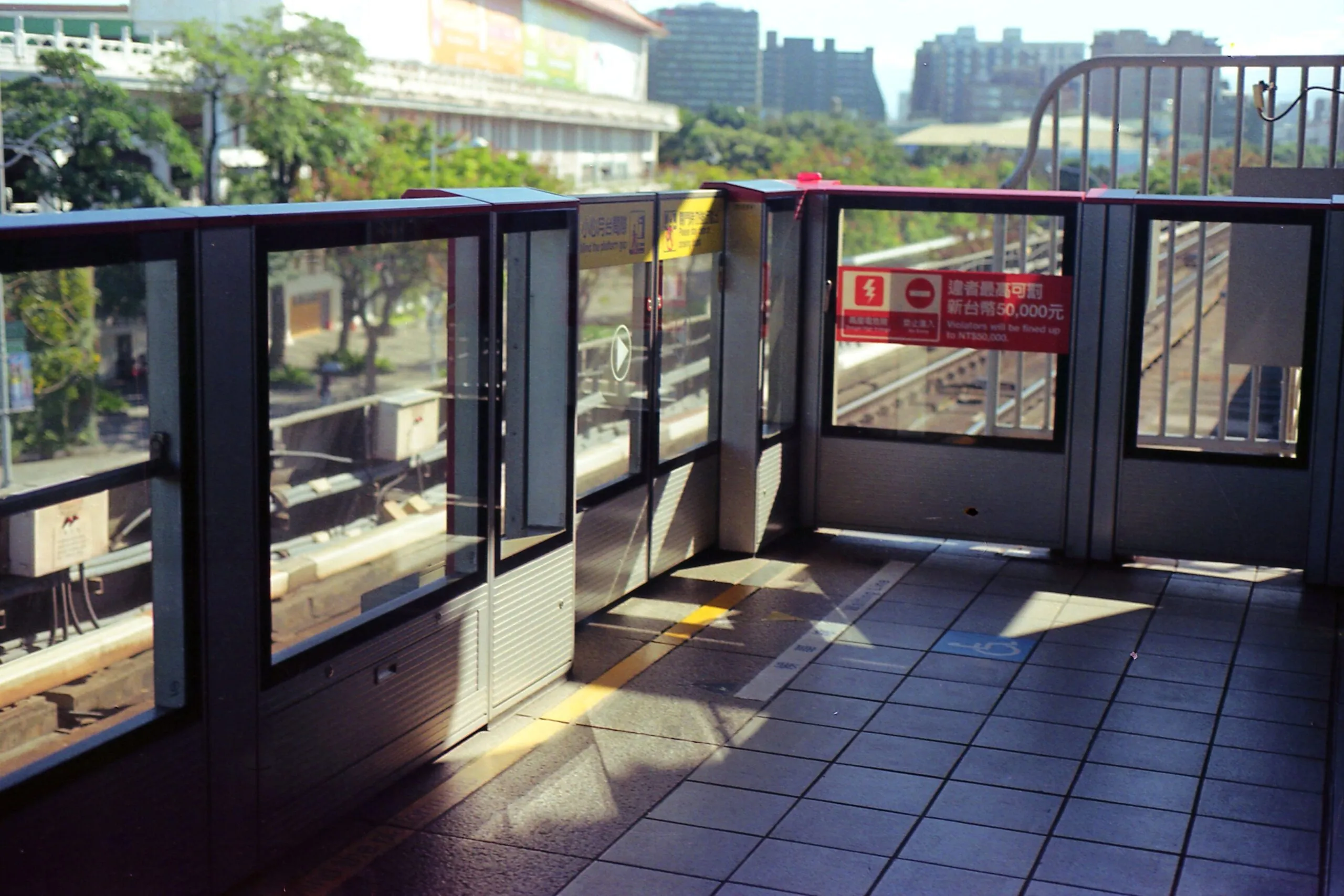 Ein sonniger Bahnsteig der Taipei Metro mit Bahnsteigtüren verläuft parallel zu den Gleisen.