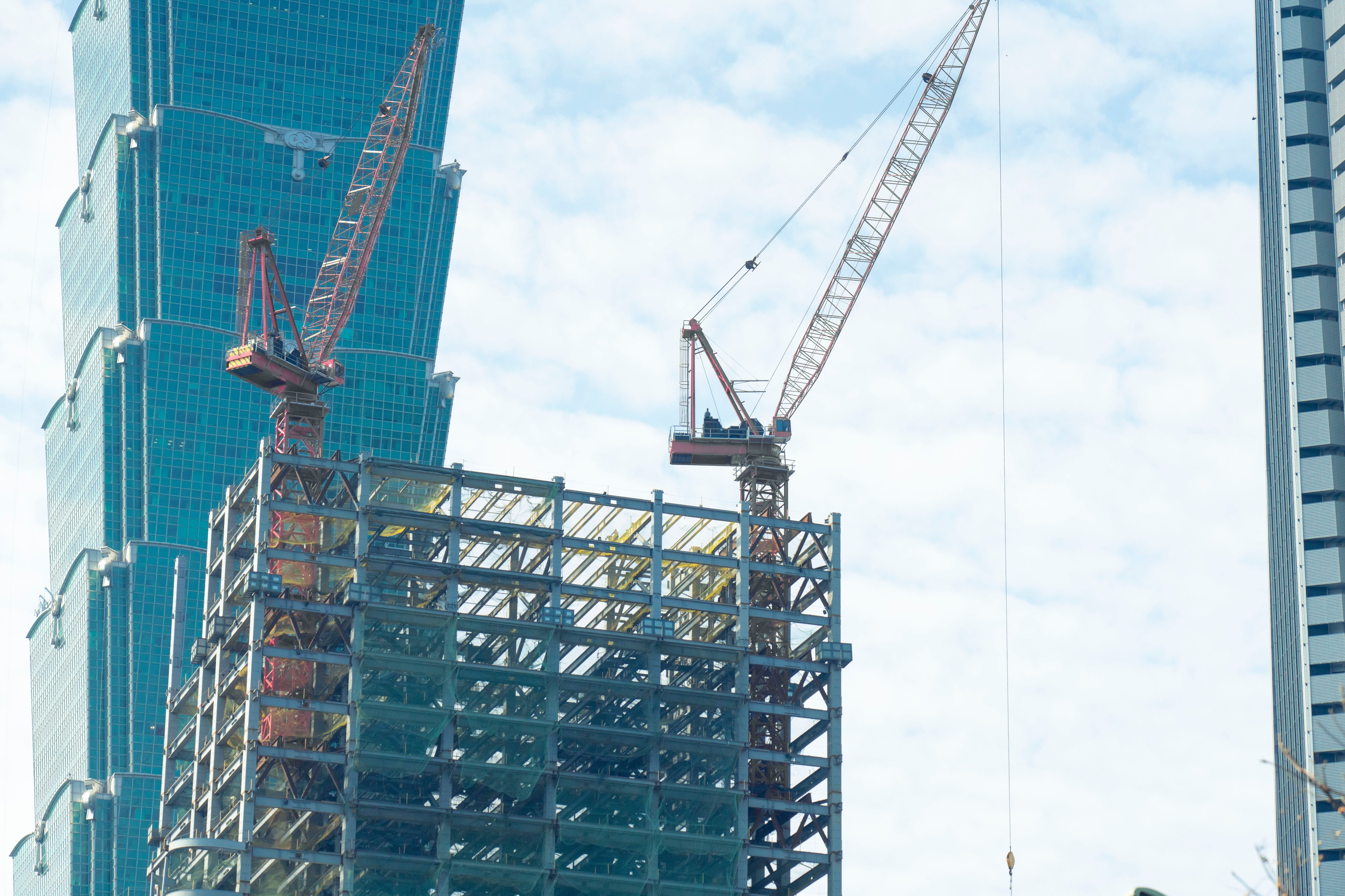 Baukräne ragen über einer innerstädtischen Baustelle in der Skyline von Taipei auf.