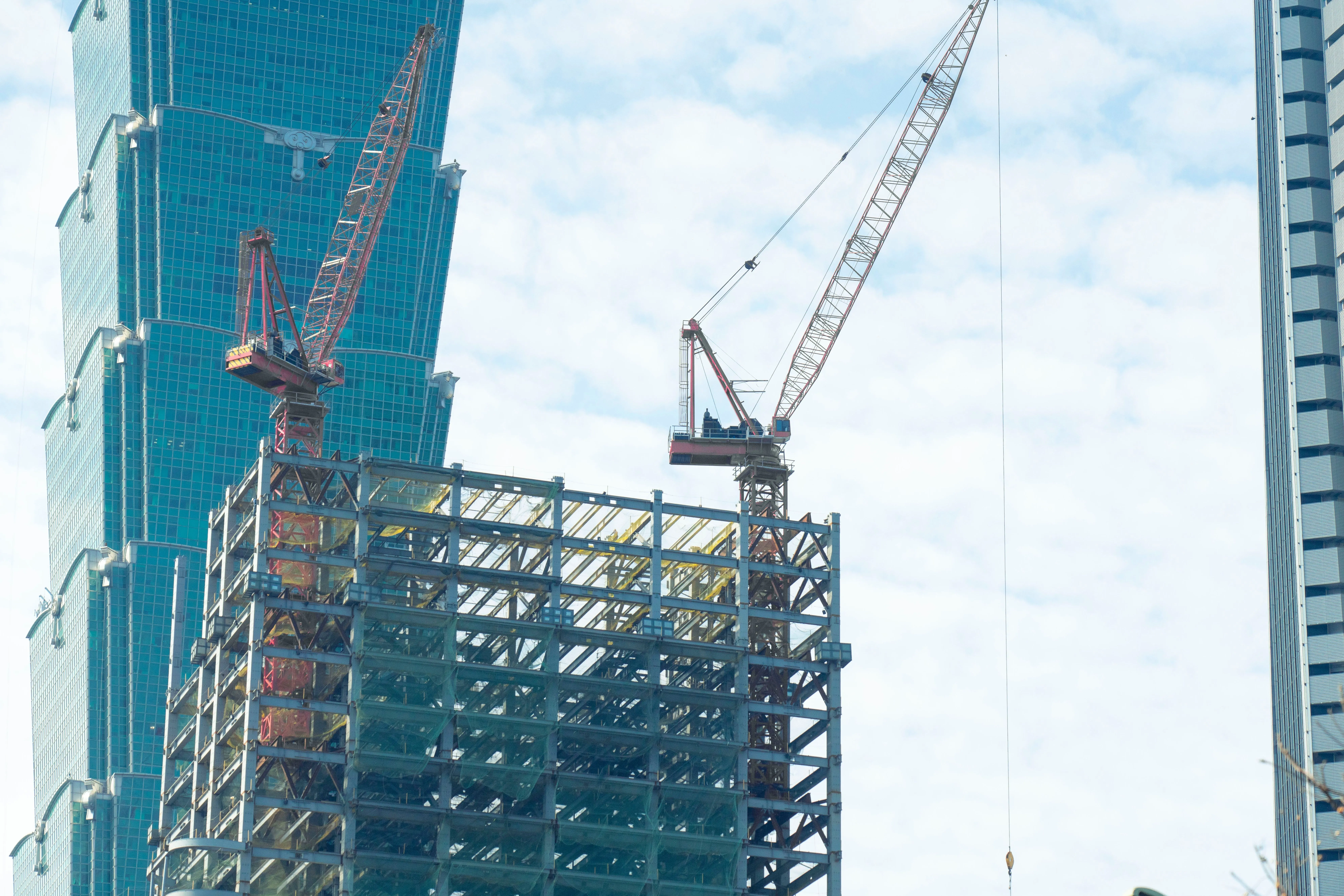 Baukräne ragen über einer innerstädtischen Baustelle in der Skyline von Taipei auf.