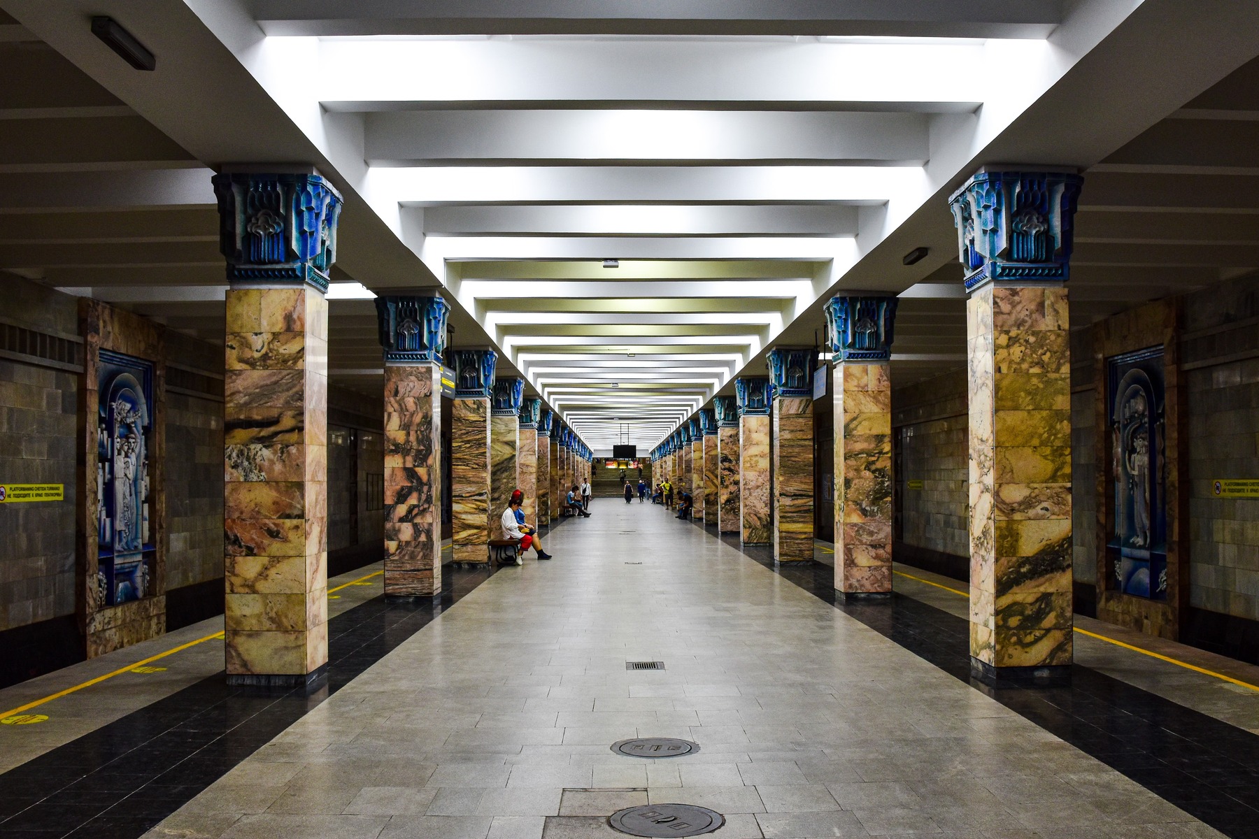 The image shows a distinctive Tashkent Metro station hall lined with marble columns.