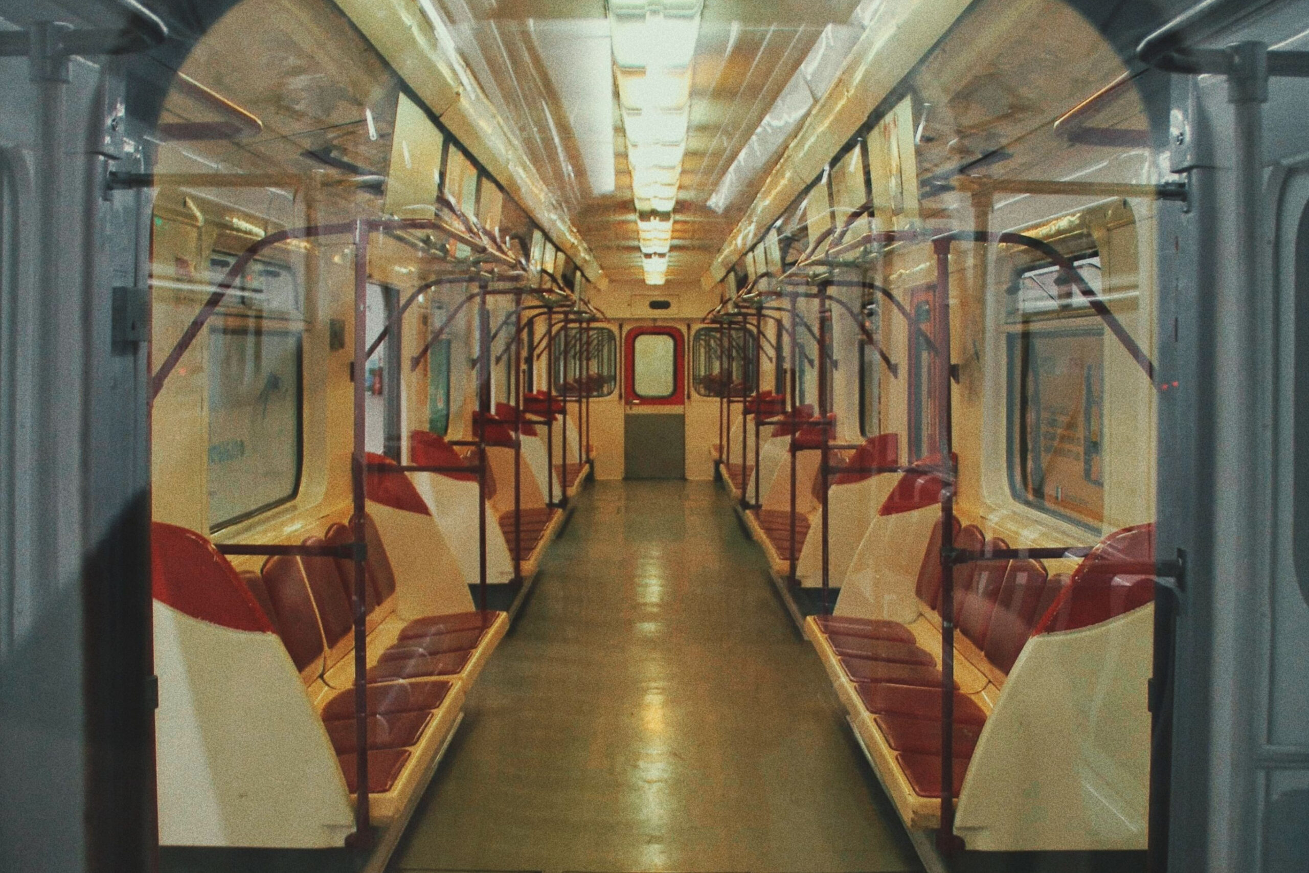 An empty Tbilisi Metro carriage with red seats is viewed through an open doorway.
