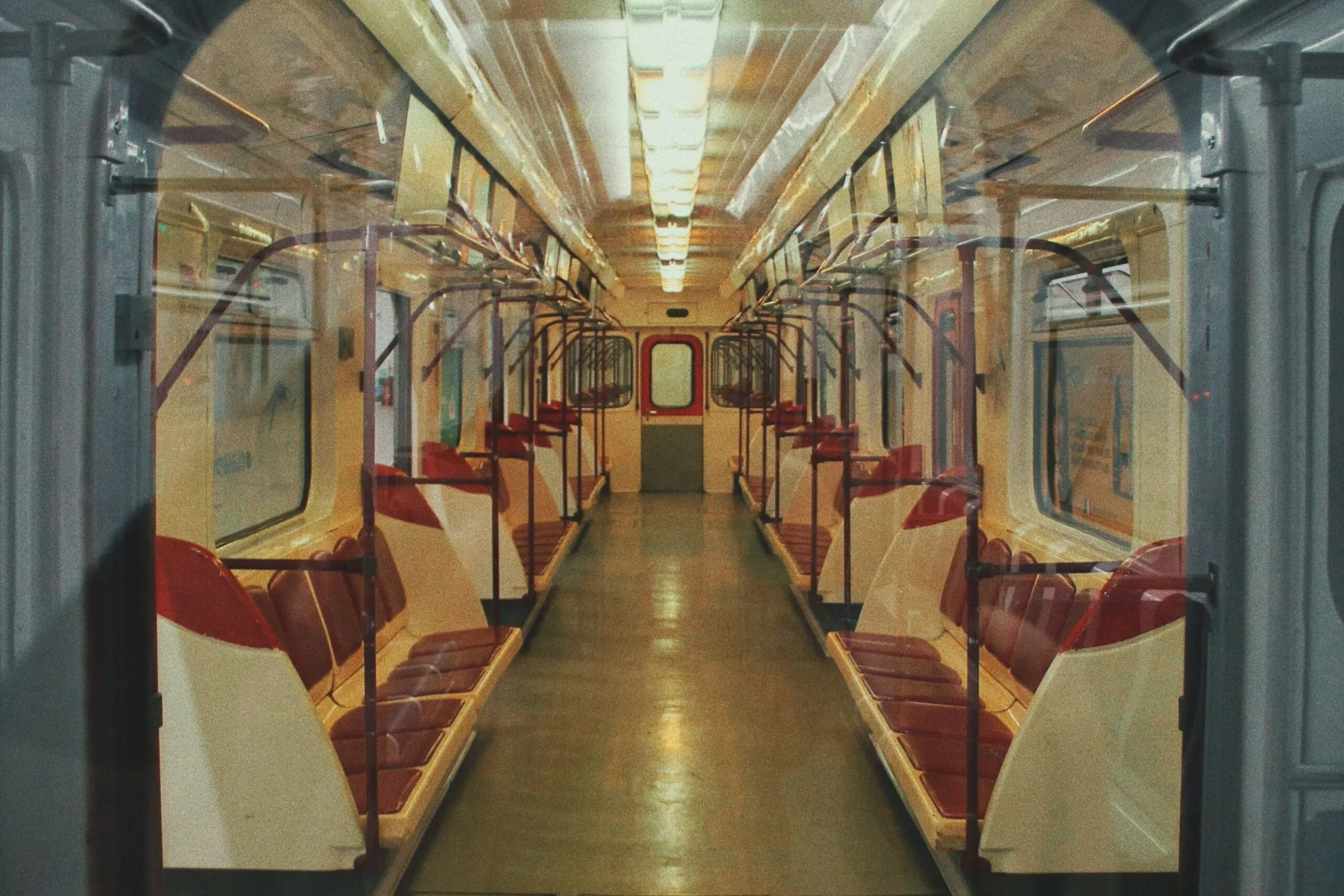 An empty Tbilisi Metro carriage with red seats is viewed through an open doorway.